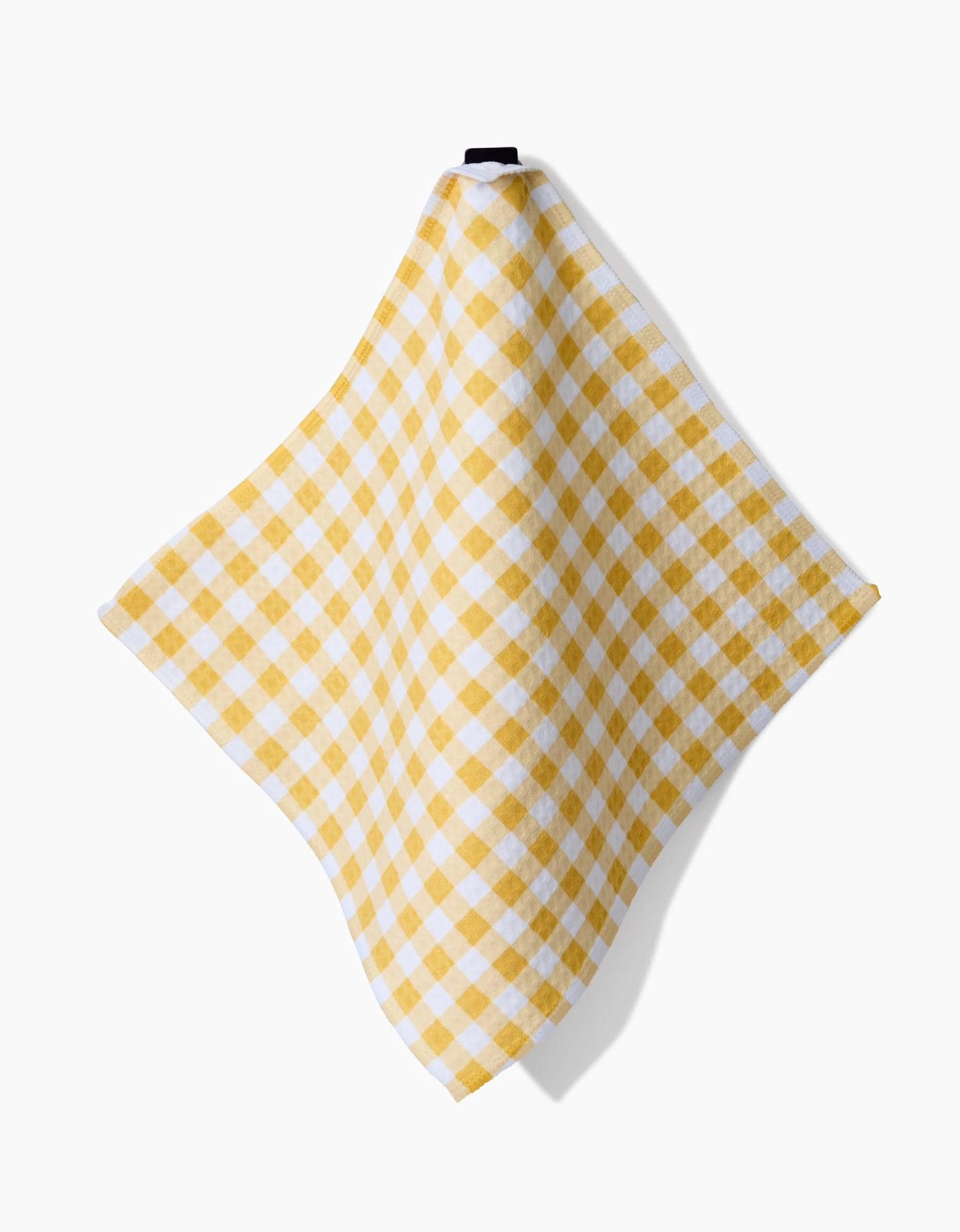 A Danelys Sidron Golden Plaid washcloth in yellow and white checkers hangs from a hook against a plain white background.