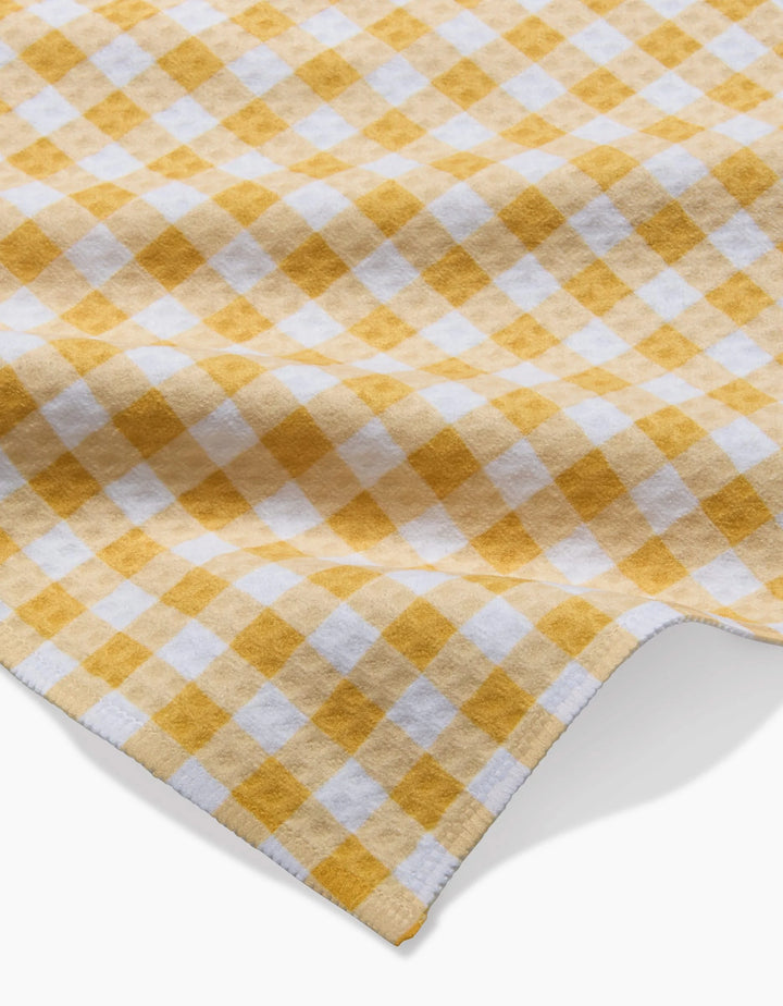 A close-up of the Golden Plaid Luxe Washcloth by Danelys Sidron, featuring a yellow and white plaid pattern with a soft, textured Geoweave fabric, slightly wrinkled to highlight its repeating checkered design.