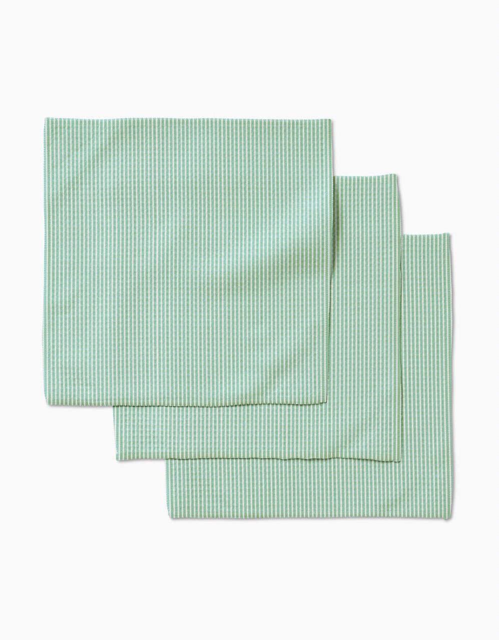 Three Half and Half cloth napkins by GEOMETRY, in light green and white stripes with ultra-absorbent Geoweave technology, are neatly folded and slightly overlapping on a plain white background.