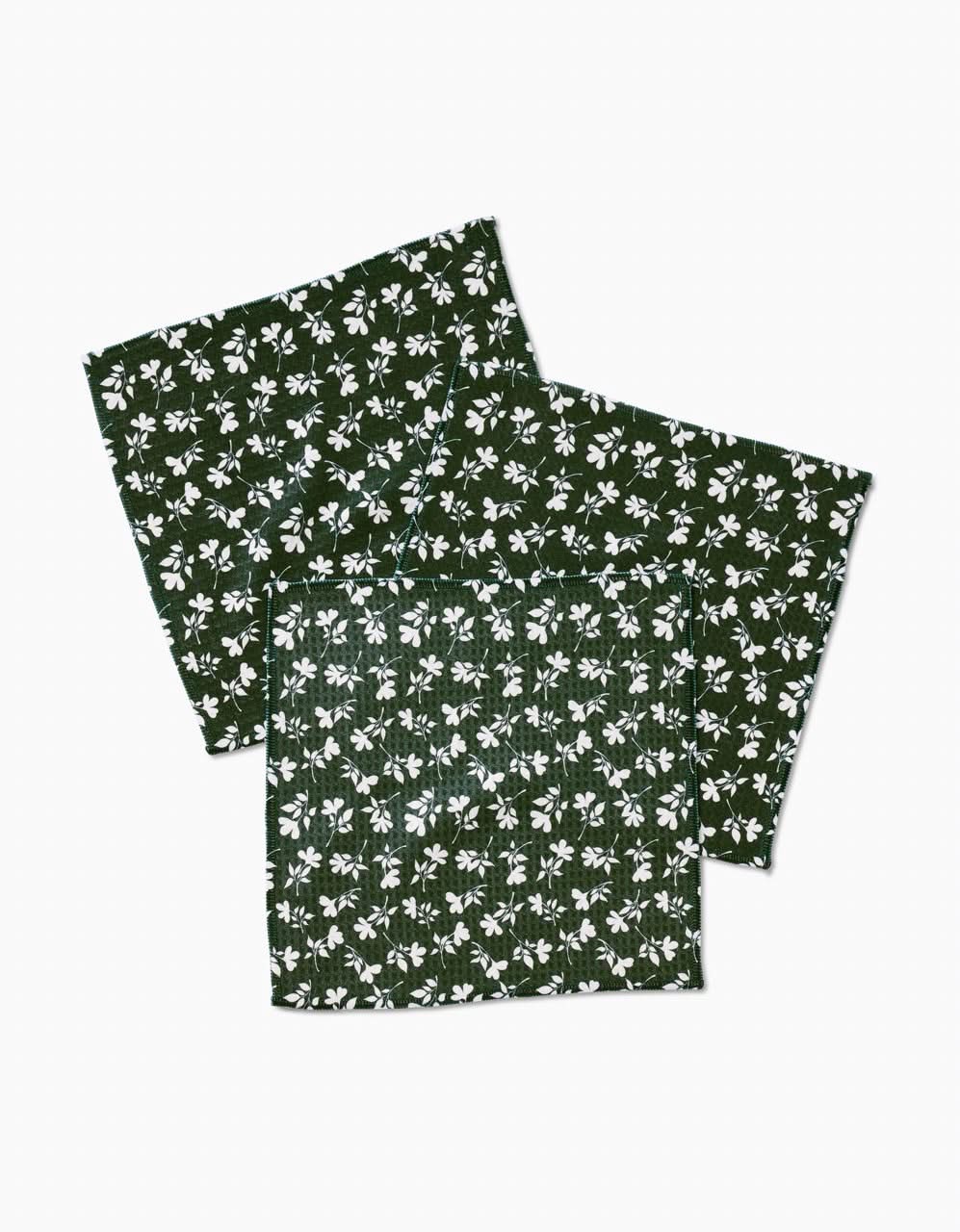 Three dark green Penelope cloth napkins by Charlie Rowan Designs, with a white floral pattern and Geoweave technology for ultra-absorbency like a Luxe Washcloth, are arranged overlapping on a plain white background.