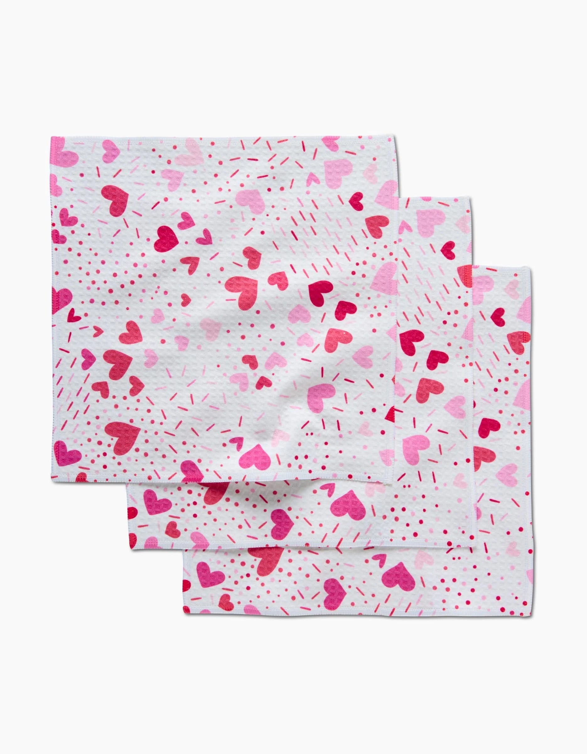 Three Sprinkled With Love napkins by Rebecca Bobko, featuring pink and red hearts, dots, and lines on white—perfect for adding a charming touch to any setting.
