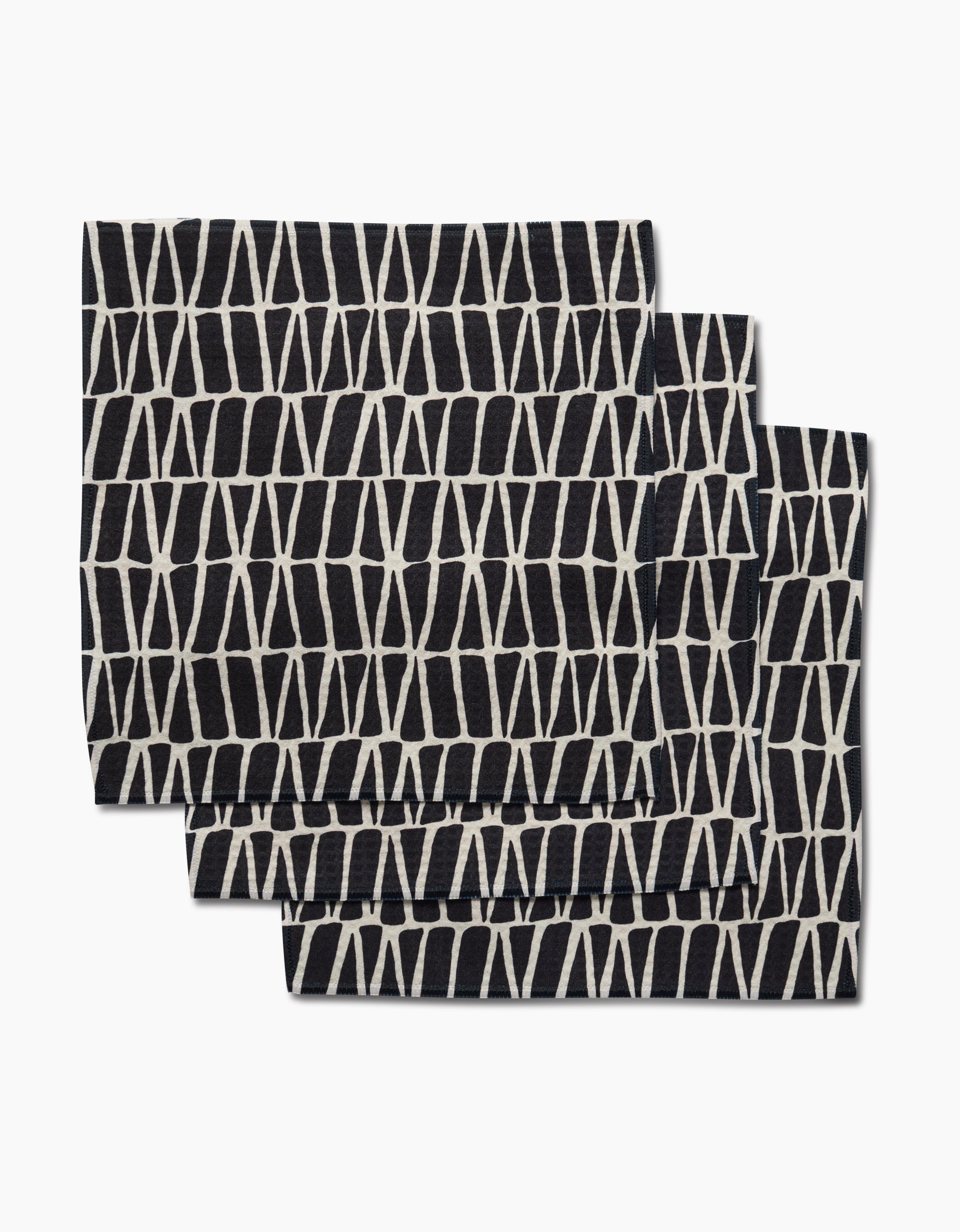 Three folded black Rosa Kichline Textured Geometry washcloths, each featuring a white geometric crisscross pattern, are shown overlapping on a plain white background.