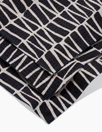 A close-up of Rosa Kichlines Textured Geometry towels—crafted from recycled materials—showcasing a bold black and white abstract pattern of irregular geometric blocks.