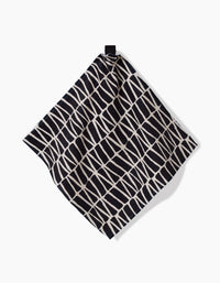 The Rosa Kichline Textured Geometry washcloth, featuring a black and white irregular grid pattern, hangs from a black loop against a plain white background.