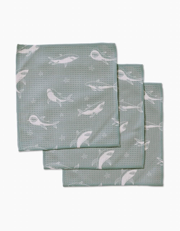 Three folded Toothy Tales washcloths by Janna Sue Design, in green with a textured surface and white whale pattern, are stacked with slight overlap on a plain white background. Made from recycled materials, theyre ultra-absorbent and eco-friendly.