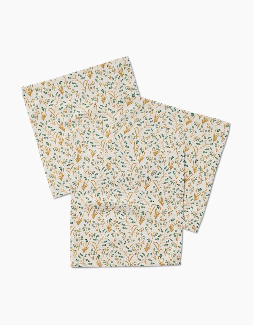 Two square Wildlight washcloths by Danelys Sidron, featuring a delicate floral pattern with yellow, blue, and green on white. Made from ultra-absorbent recycled materials and arranged overlapping.
