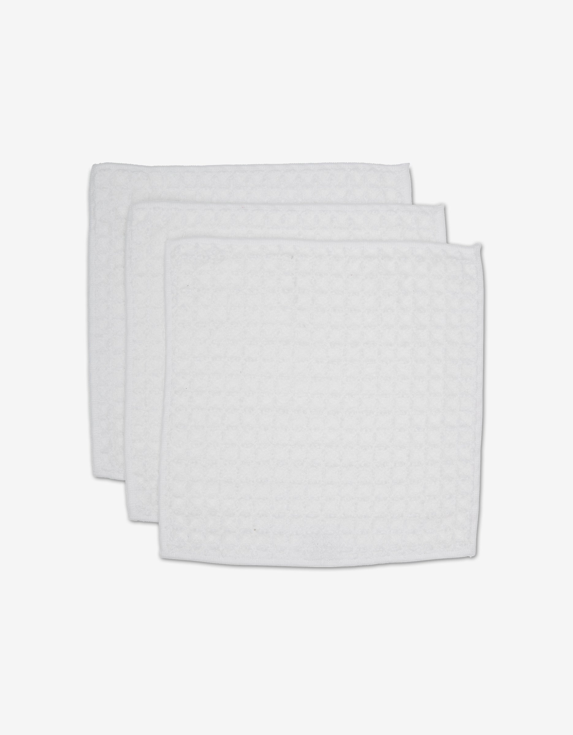 Three white, rectangular GEOMETRY Cloud waffle washcloths with a textured pattern are stacked on a white background, adding spa-like comfort and luxury to your towel collection.
