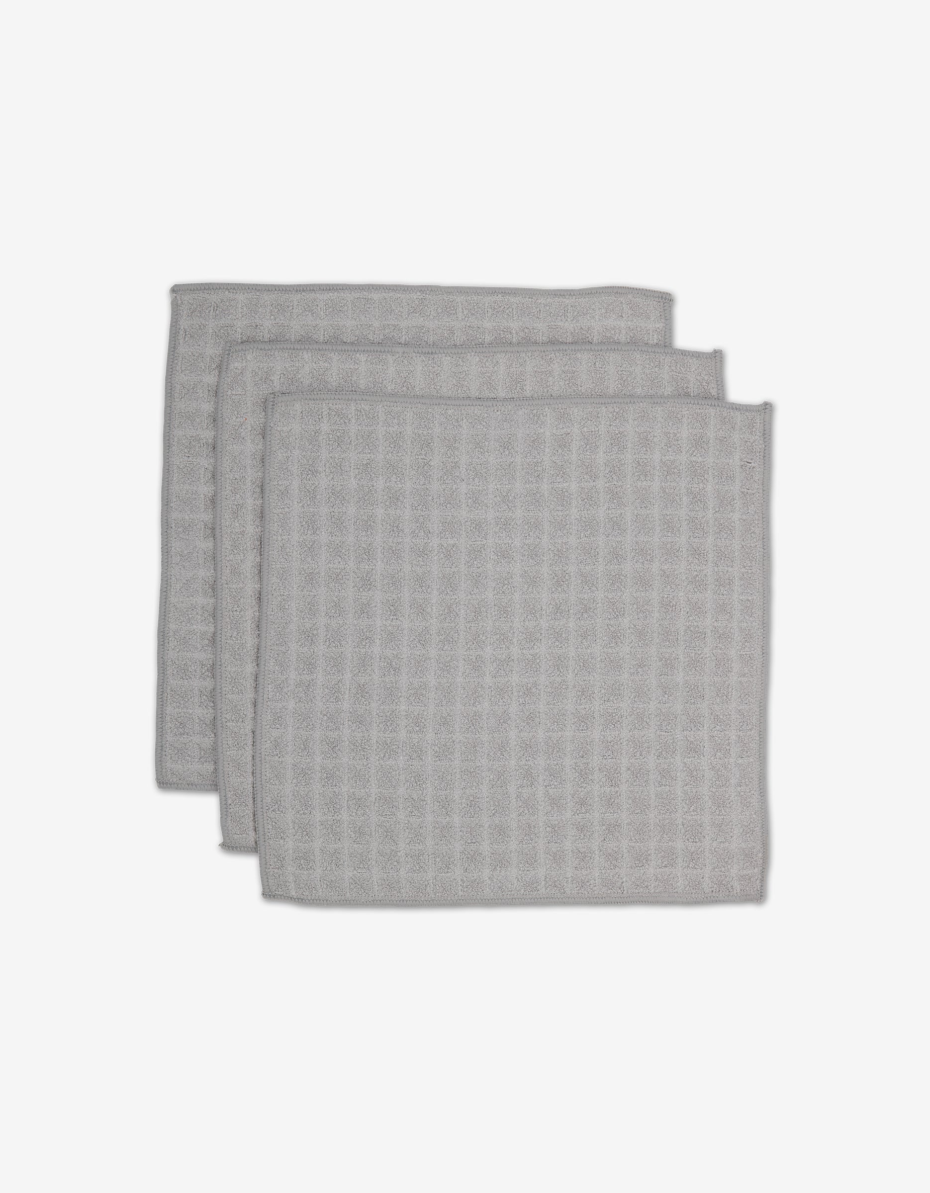 Three light gray GEOMETRY Stone Waffle Washcloths with a waffle texture are stacked slightly offset on a plain white background.
