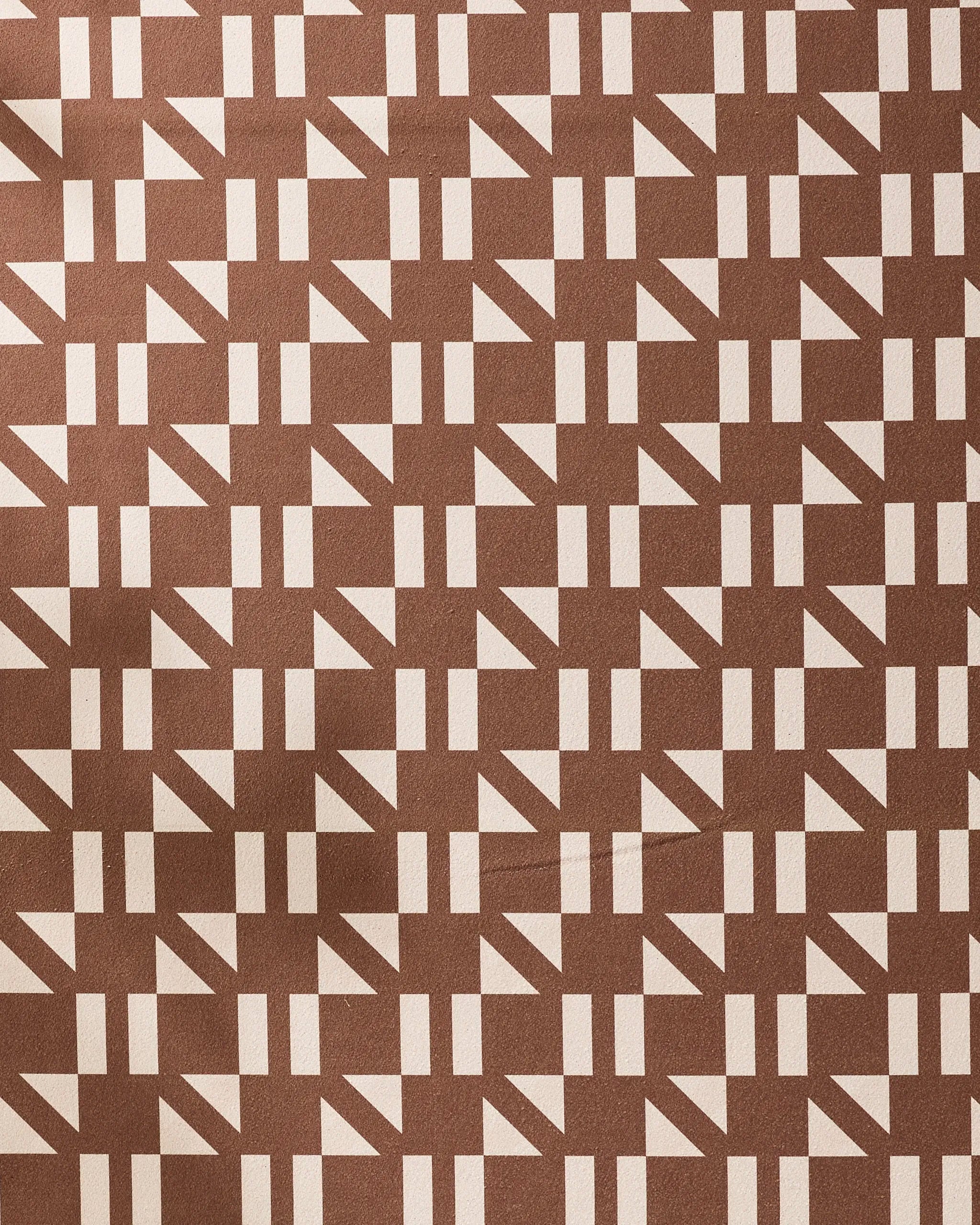 The Affogato yoga towel by Geometry features a modern brown fabric with beige geometric triangles and rectangles in a repeating grid, offering an abstract, slip-resistant design for your next yoga session.