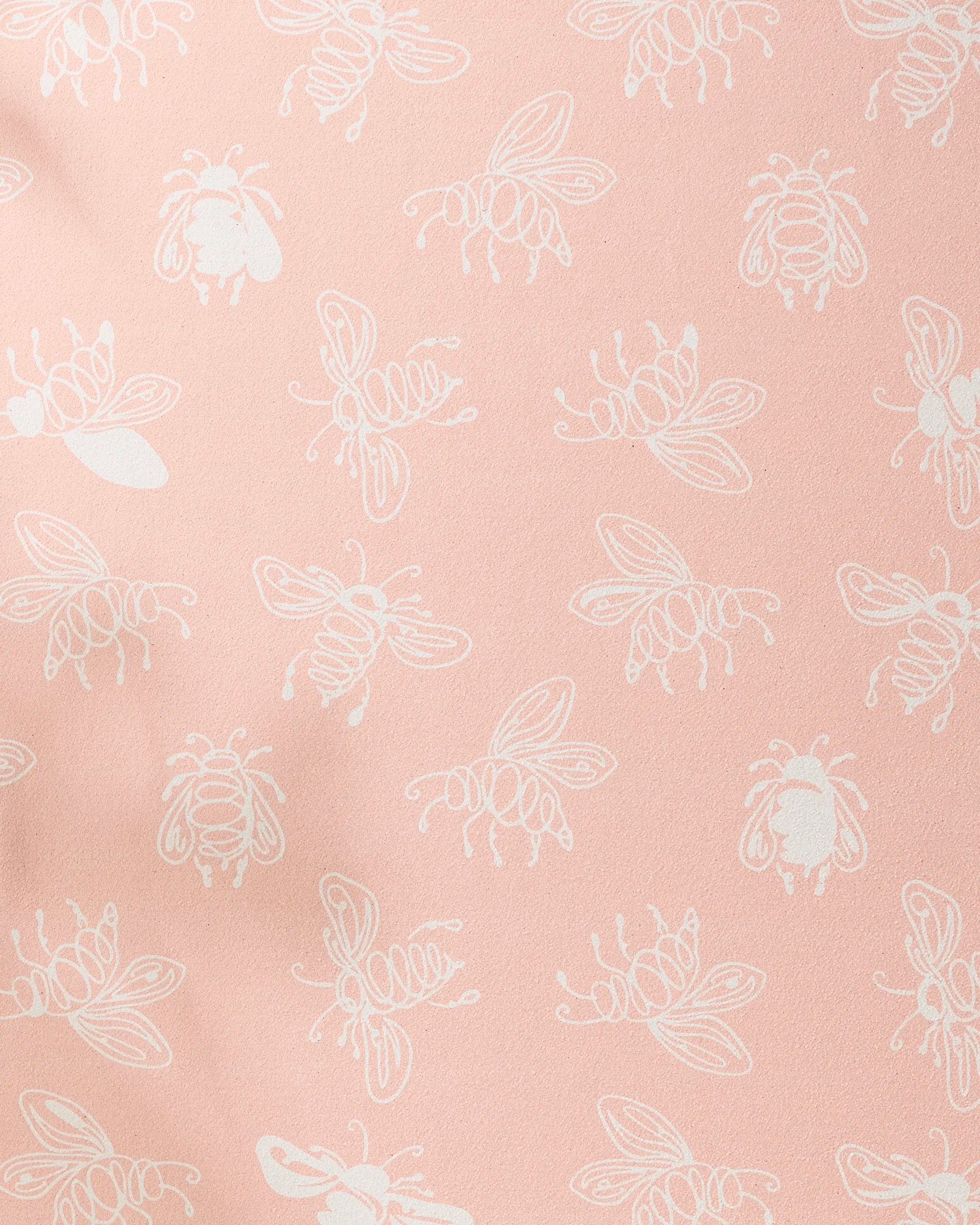 The Sara Mari Beelieve yoga towel features a playful pattern of white bee line drawings scattered over a soft pink, non-slip surface.
