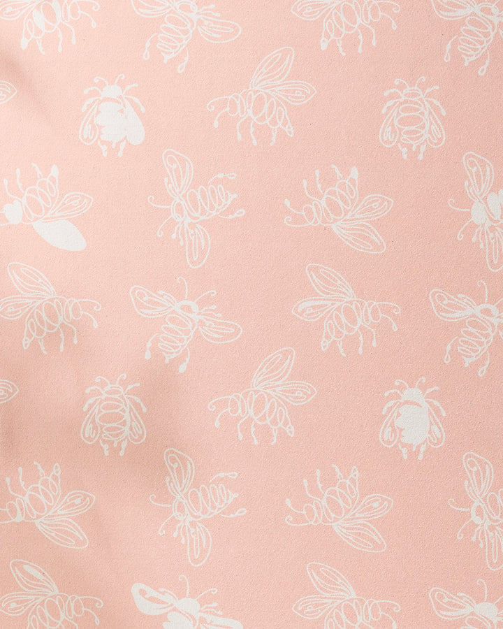 The Sara Mari Beelieve yoga towel features a playful pattern of white bee line drawings scattered over a soft pink, non-slip surface.