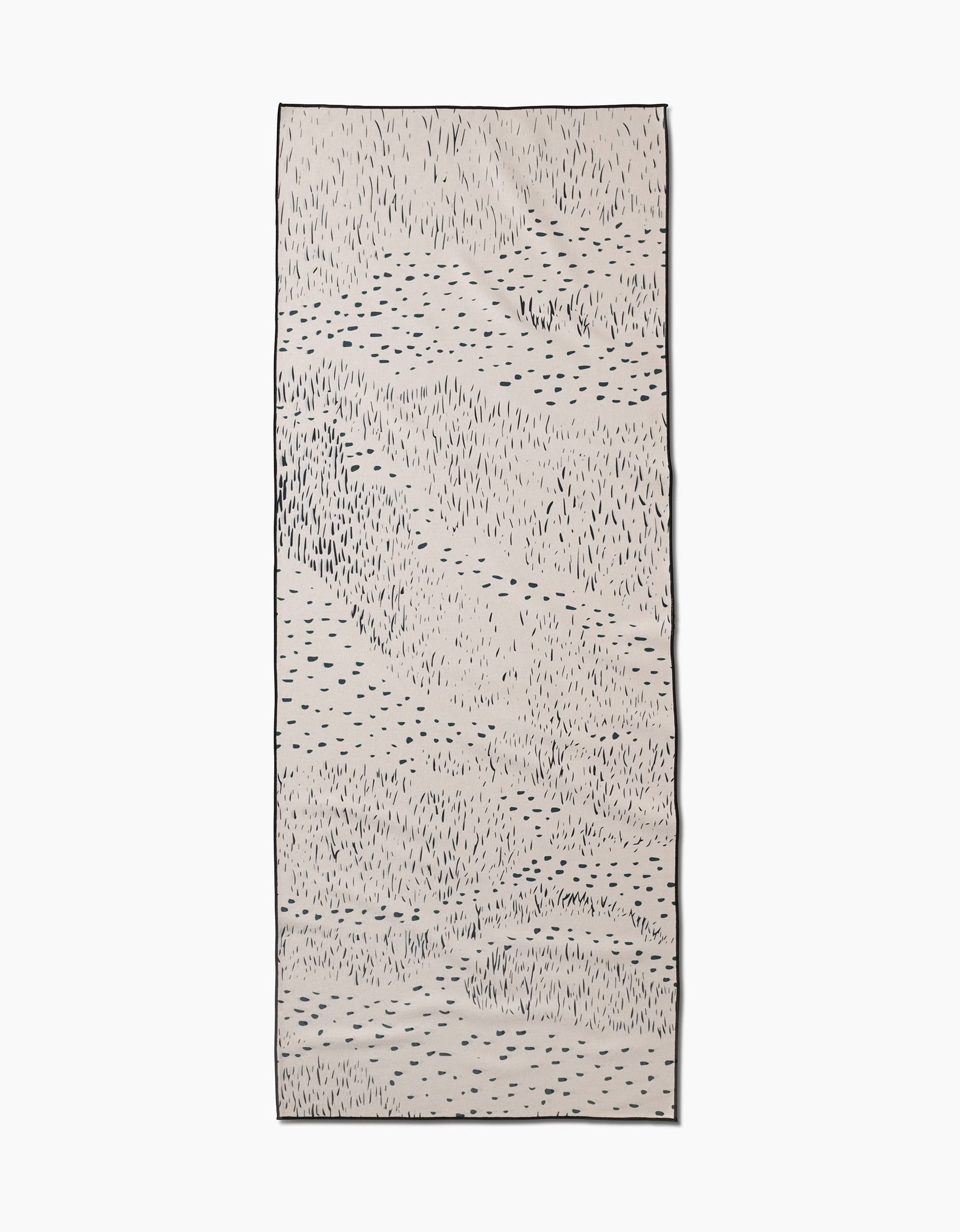 The Bend yoga towel by GEOMETRY is a rectangular beige towel with an abstract pattern of irregular black lines and small dots, bordered in black. Designed for non-slip stability, it’s perfect for enhancing your yoga practice.