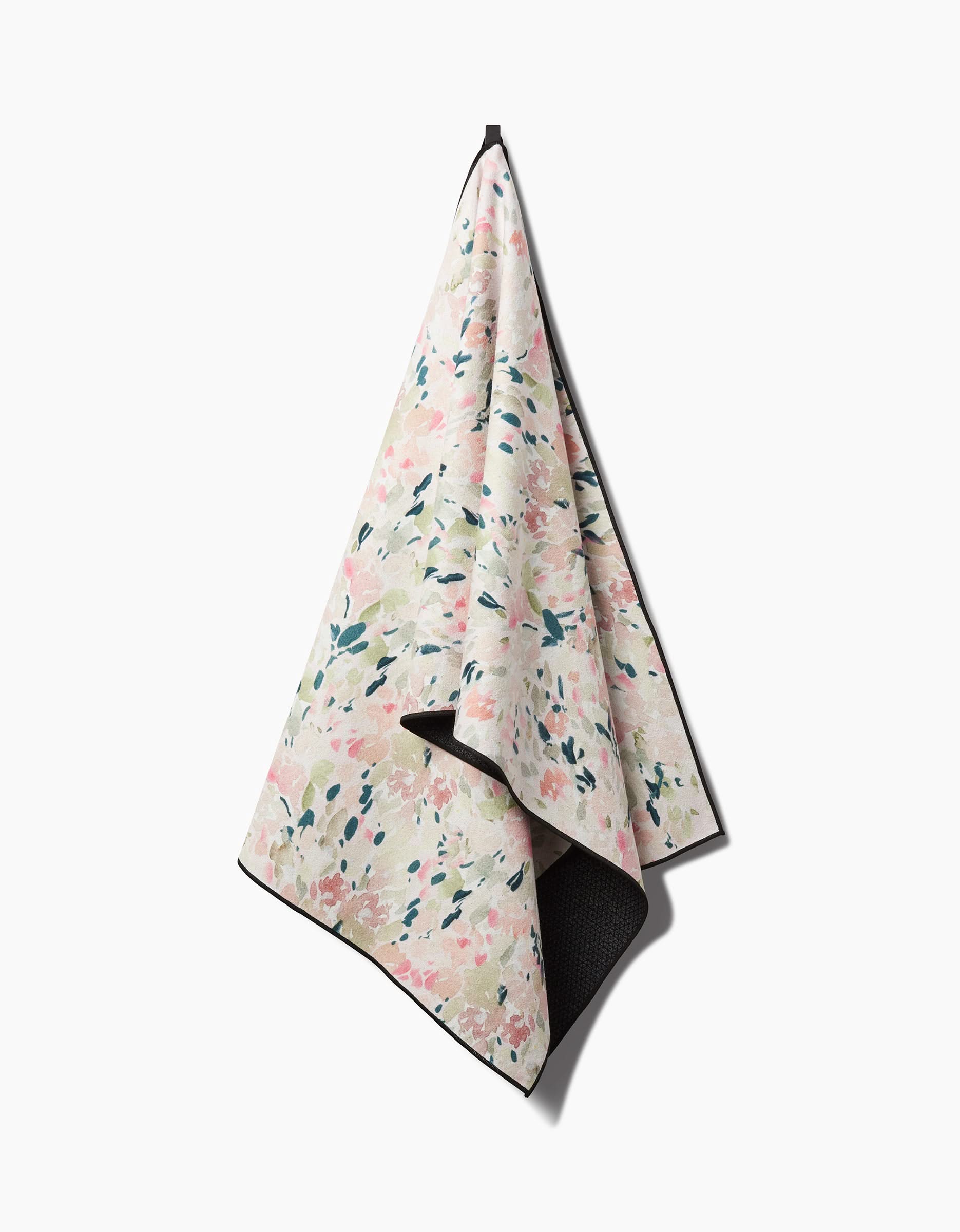The Blossoms yoga towel by Anee Shah features a pastel abstract floral design in pink, green, and blue on a white background, with dark edges, black inner lining, and is made from recycled materials.