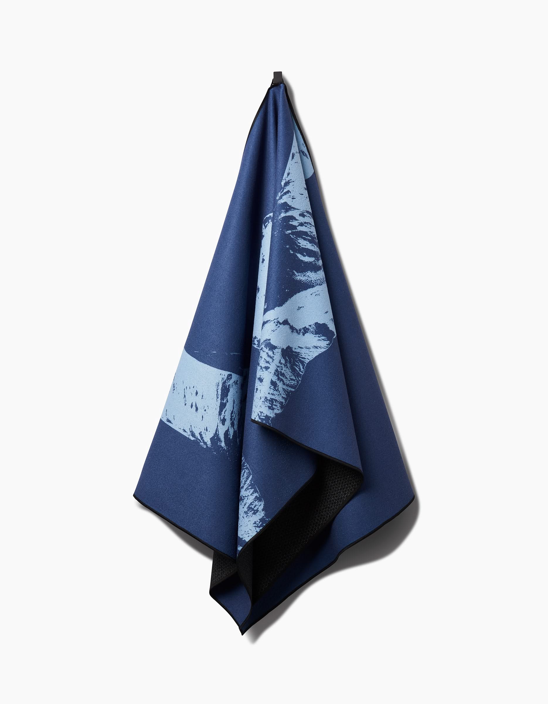 The Blue Moon yoga towel by Graphics and Grain features light blue abstract patterns and hangs on a hook against a white background, making it the ideal slip-resistant accessory for your yoga practice.