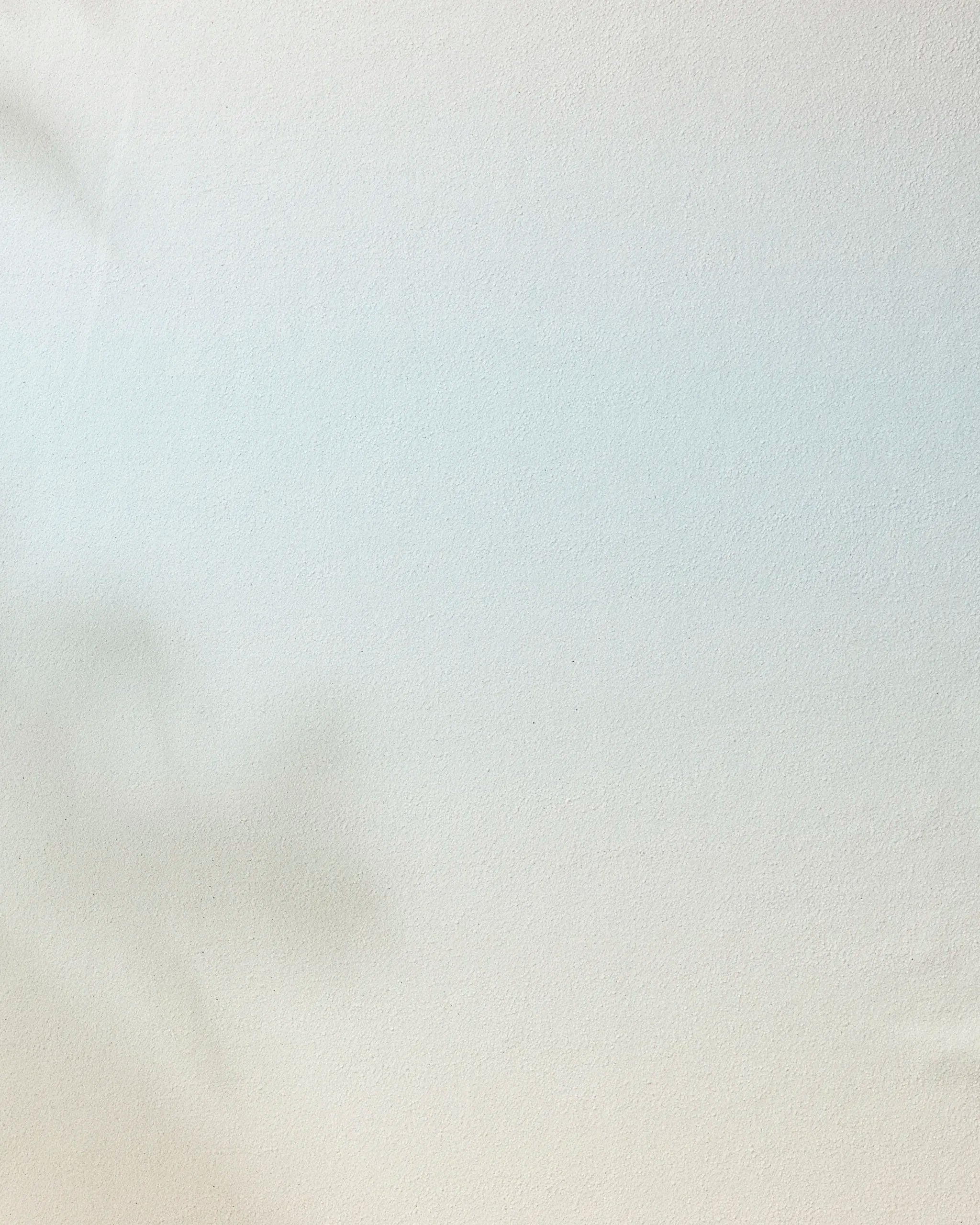 A faint plant shadow appears on a smooth, light surface, creating a soft and minimal backdrop—perfect for highlighting the Breathe non-slip yoga towel by GEOMETRY.