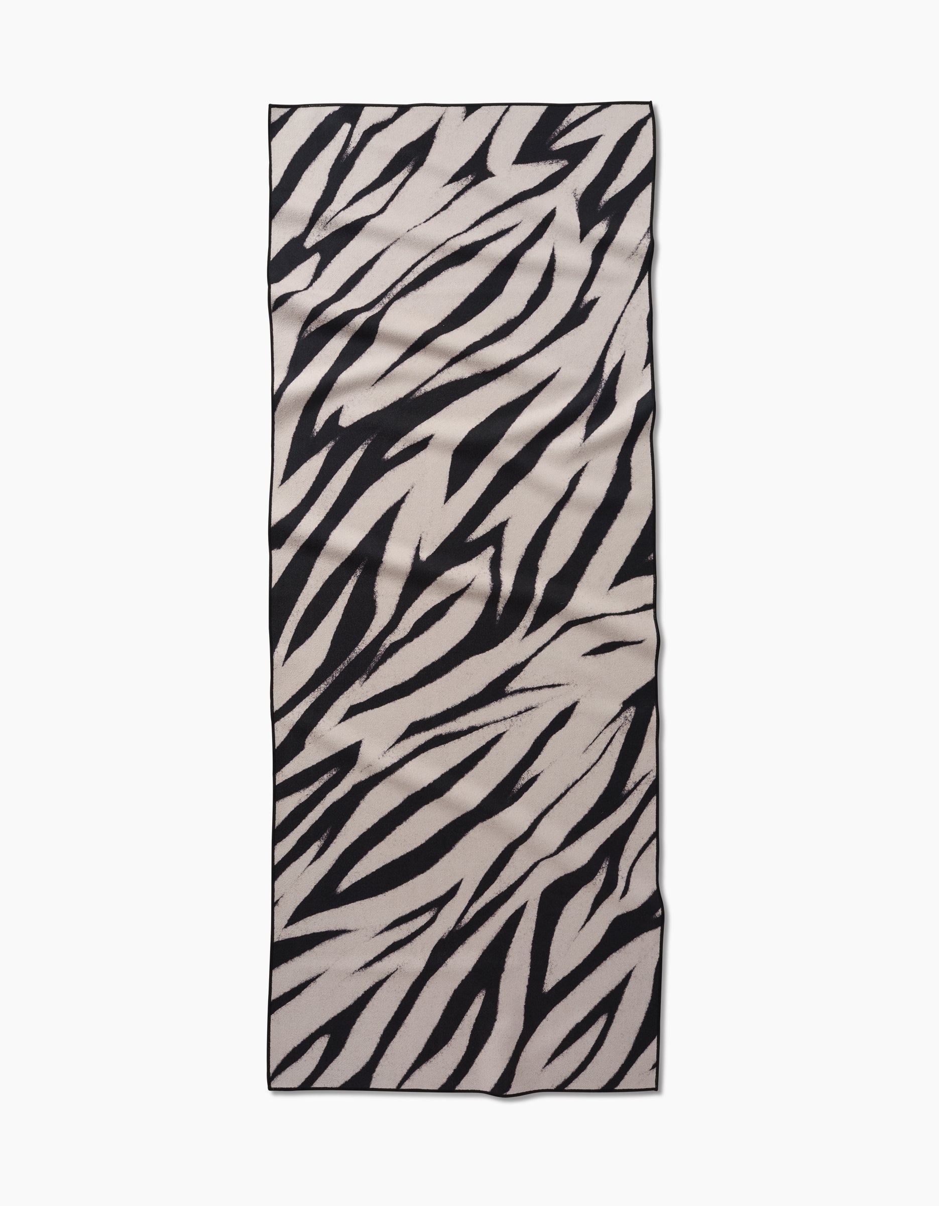 The GEOMETRY Chase yoga towel features a black and white zebra stripe pattern, crafted from recycled materials, displayed on a flat white background.