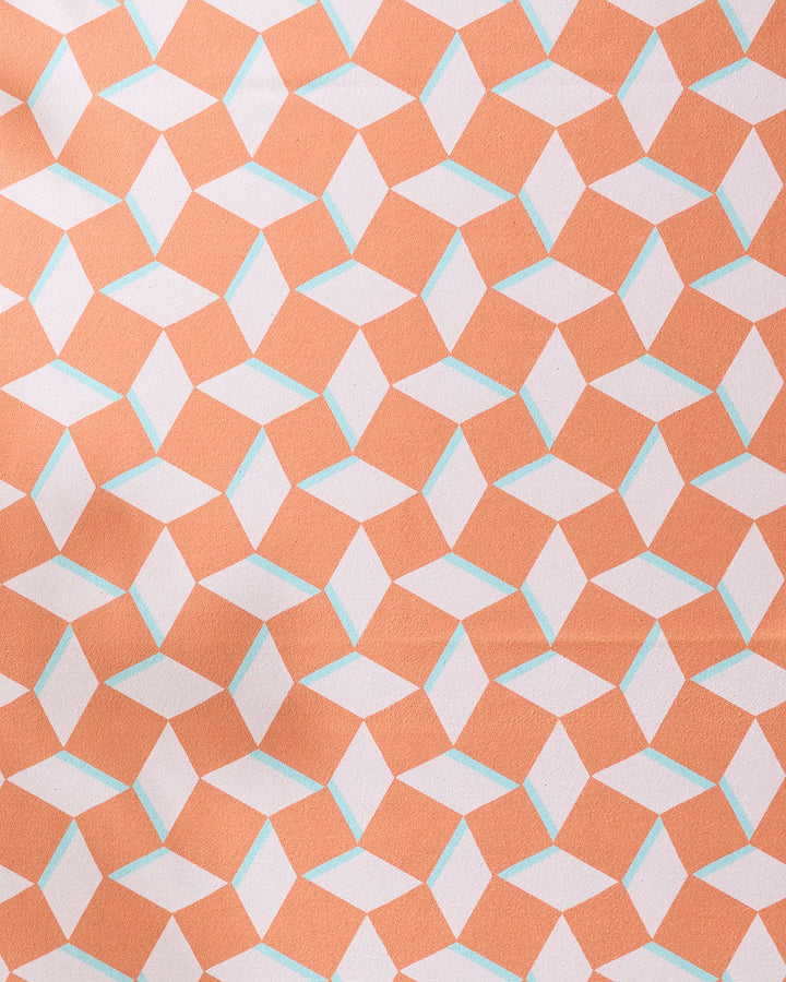 The Geometry Circus Stand Pink Orange yoga towel features interlocking orange, white, and light blue shapes forming a 3D cube illusion. Its non-slip fabric surface is slightly textured and wrinkled for added grip.