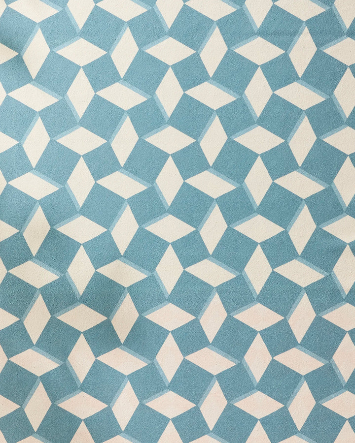 The Geometry Circus Stand Teal Cream features a blue and white geometric diamond pattern that creates an interlocking, 3D cube effect. Its textured surface makes it the ideal non-slip yoga towel for a stable and stylish practice.