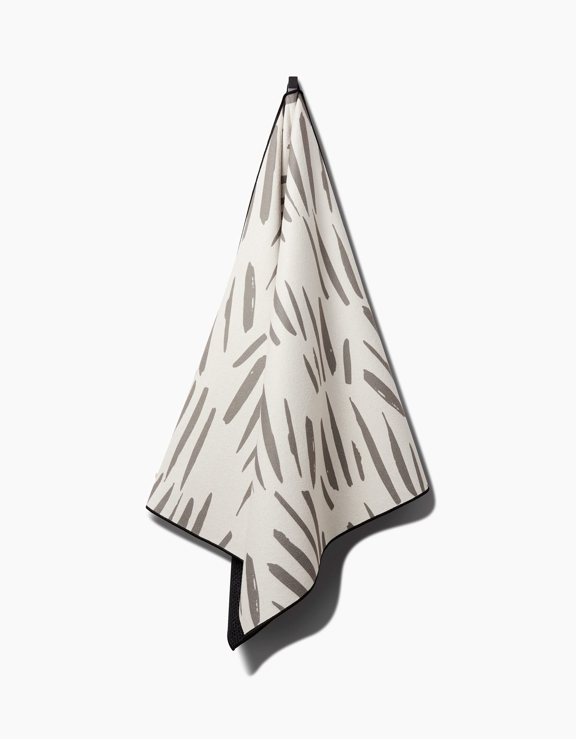 The Country Fields yoga towel by Hufton Studio features an abstract black brushstroke pattern on white, hangs from a black loop, and combines style with function for your practice.