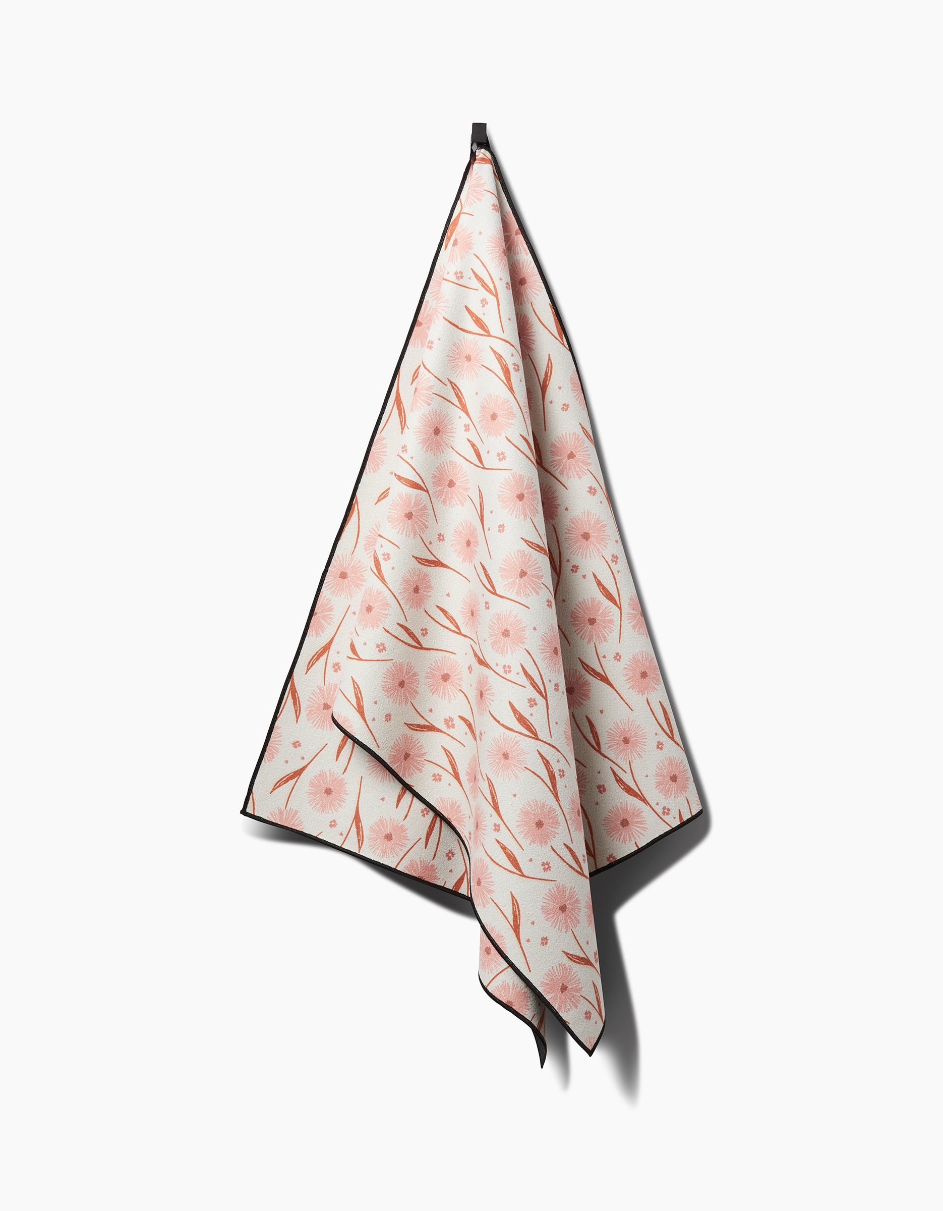 The Hufton Studio Daisy Pop yoga towel, featuring a pink floral and brown branch pattern, is hanging from a hook against a plain white background.