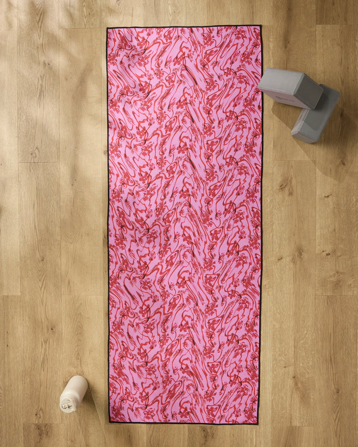 The Geometry Floral Swirls Pink yoga mat is laid out on a light wooden floor, with gray yoga blocks, a white water bottle, and a non-slip yoga towel placed nearby.