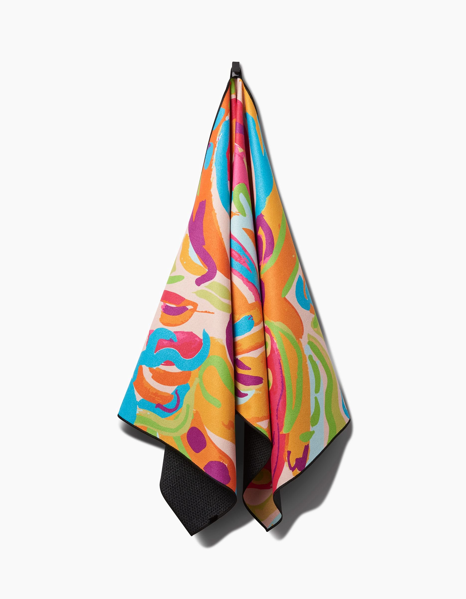 The Florescence yoga towel by Sareka Unique, featuring vibrant abstract swirls in orange, blue, pink, green, and yellow, hangs on a hook against a white background. Made from recycled materials for eco-friendliness.