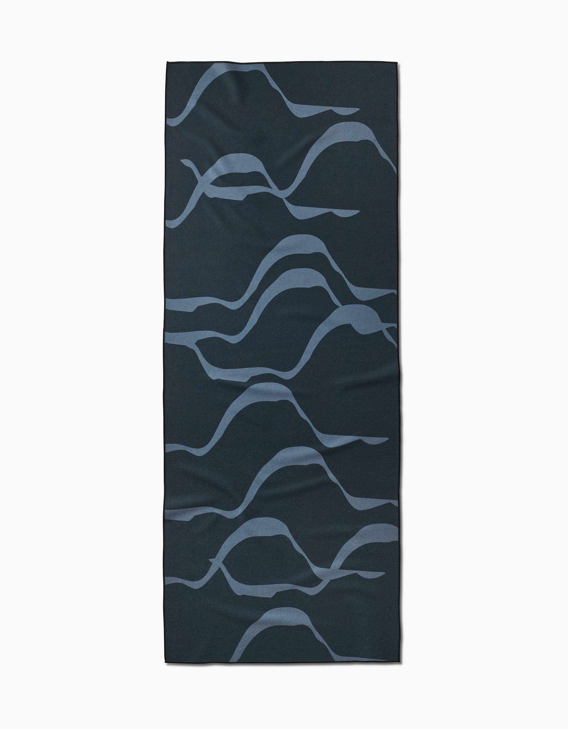 The GEOMETRY Flow yoga towel features a rectangular shape with abstract wavy blue lines and a flowing pattern, crafted from recycled materials.
