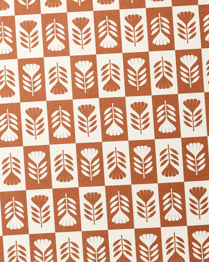 The Flower Patch yoga towel by Charlie Rowan Designs features a retro, symmetrical design with brown and white squares, each displaying a simple flower or leaf motif, all crafted on recycled material.