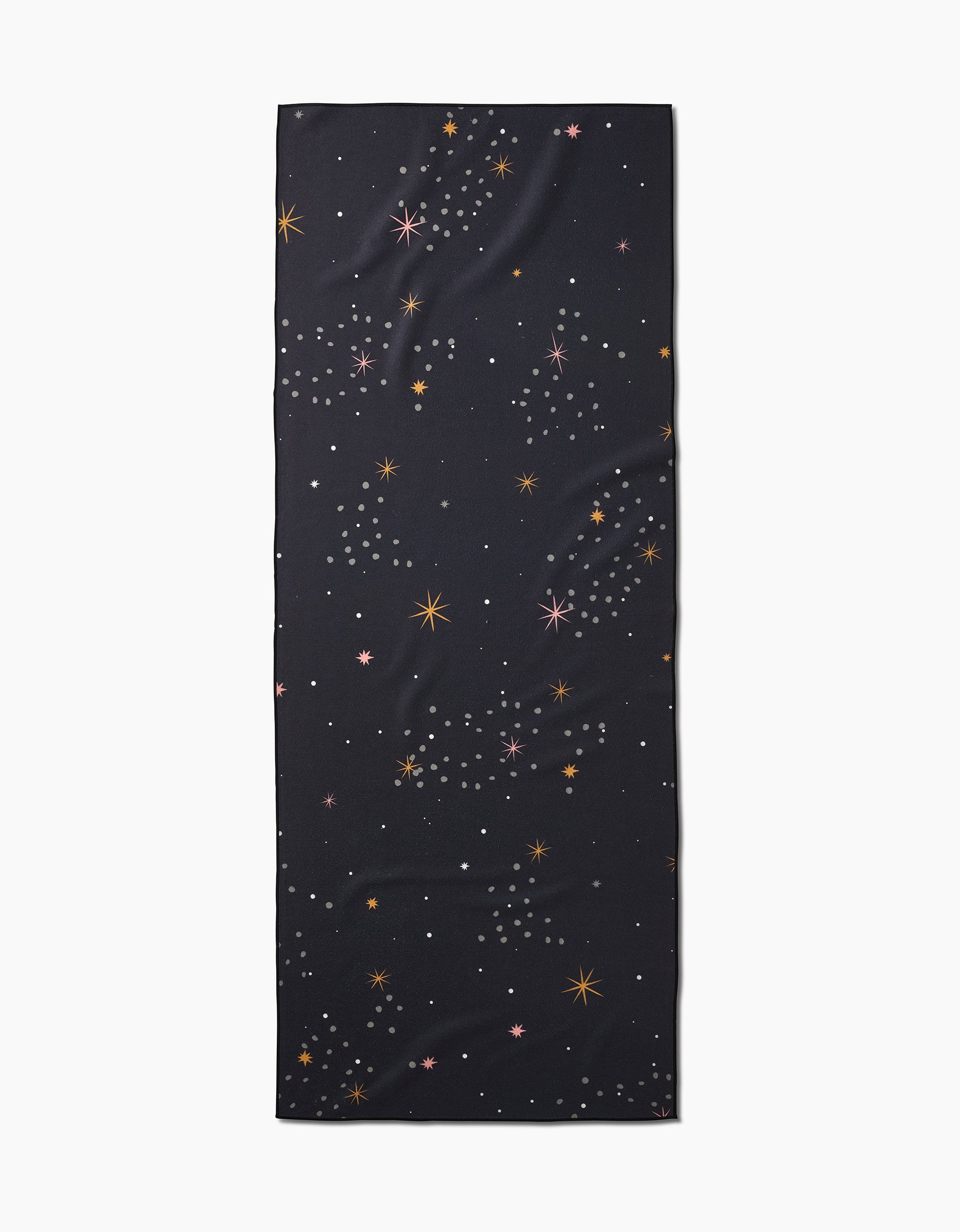 The Ash Cascade Galaxy Burst is a rectangular black recycled yoga towel featuring a multicolored scattered star pattern in orange, pink, and white, shown on a plain white background.
