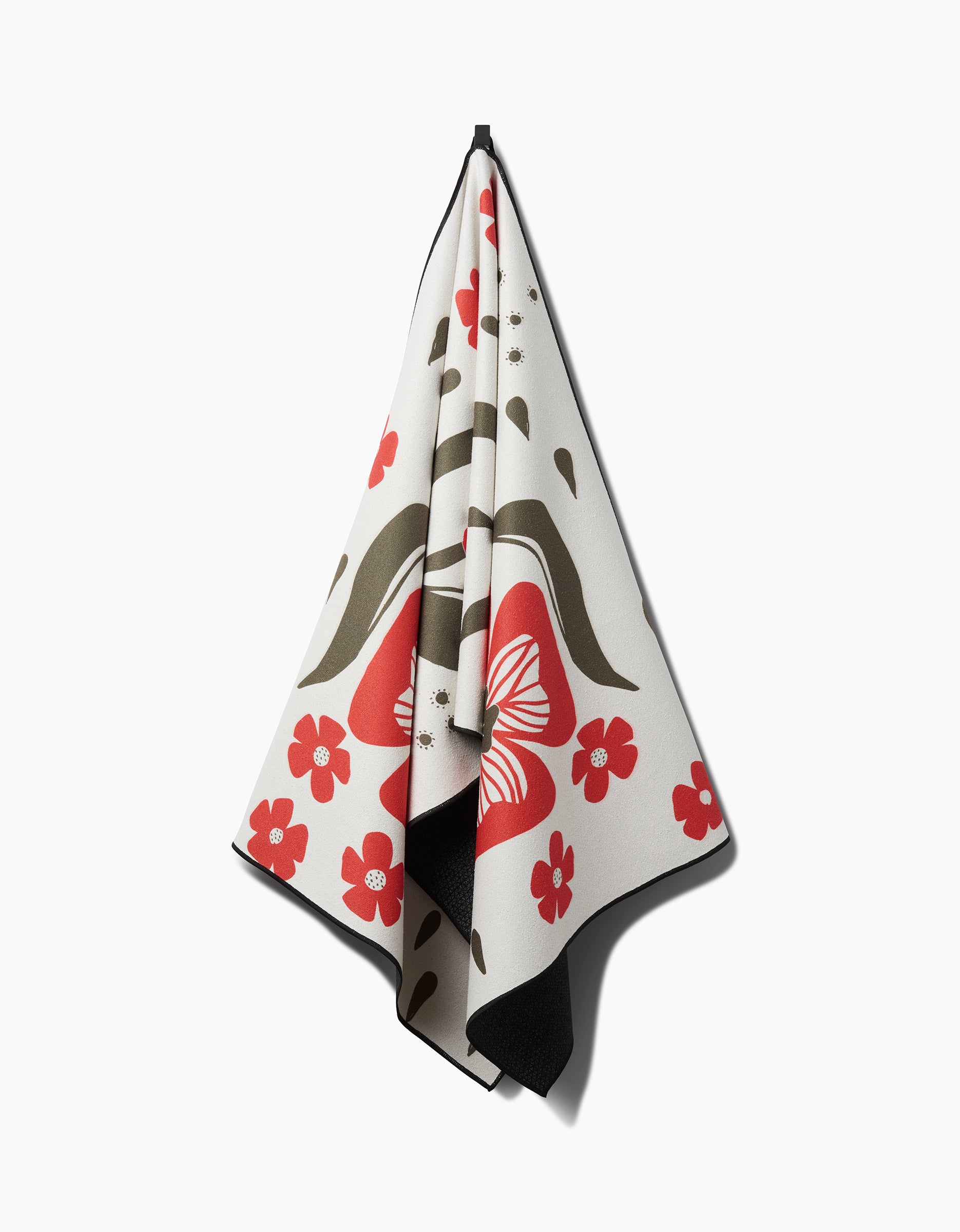 The Ash Cascade Garden Stamp yoga towel is cream-colored, made from recycled materials, and displays red flowers, a large red butterfly, and olive-green leaves, neatly arranged against a white background.