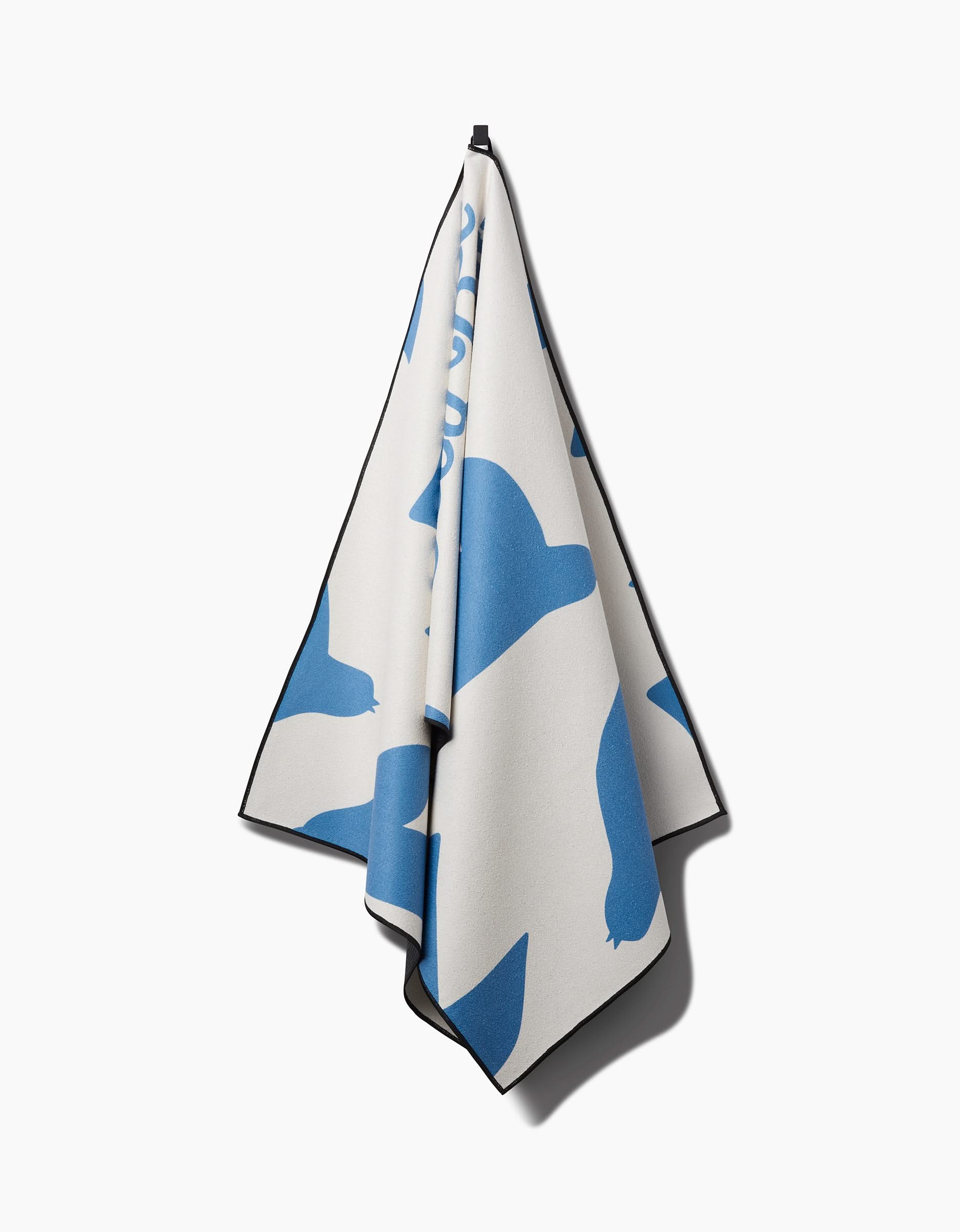 The Good Day yoga towel by Quotes by Christie, made from recycled materials, features abstract blue shapes and a dark border. It hangs from a single hook against a white background.