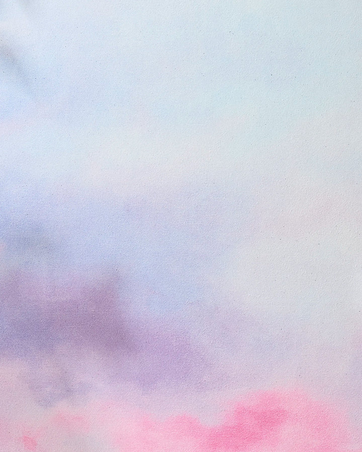 A soft pastel watercolor background with blended light blue, pink, and purple hues creates a dreamy scene—an ideal backdrop for displaying the "Magic in the Sky" recycled yoga towel by Stefanie Bales.