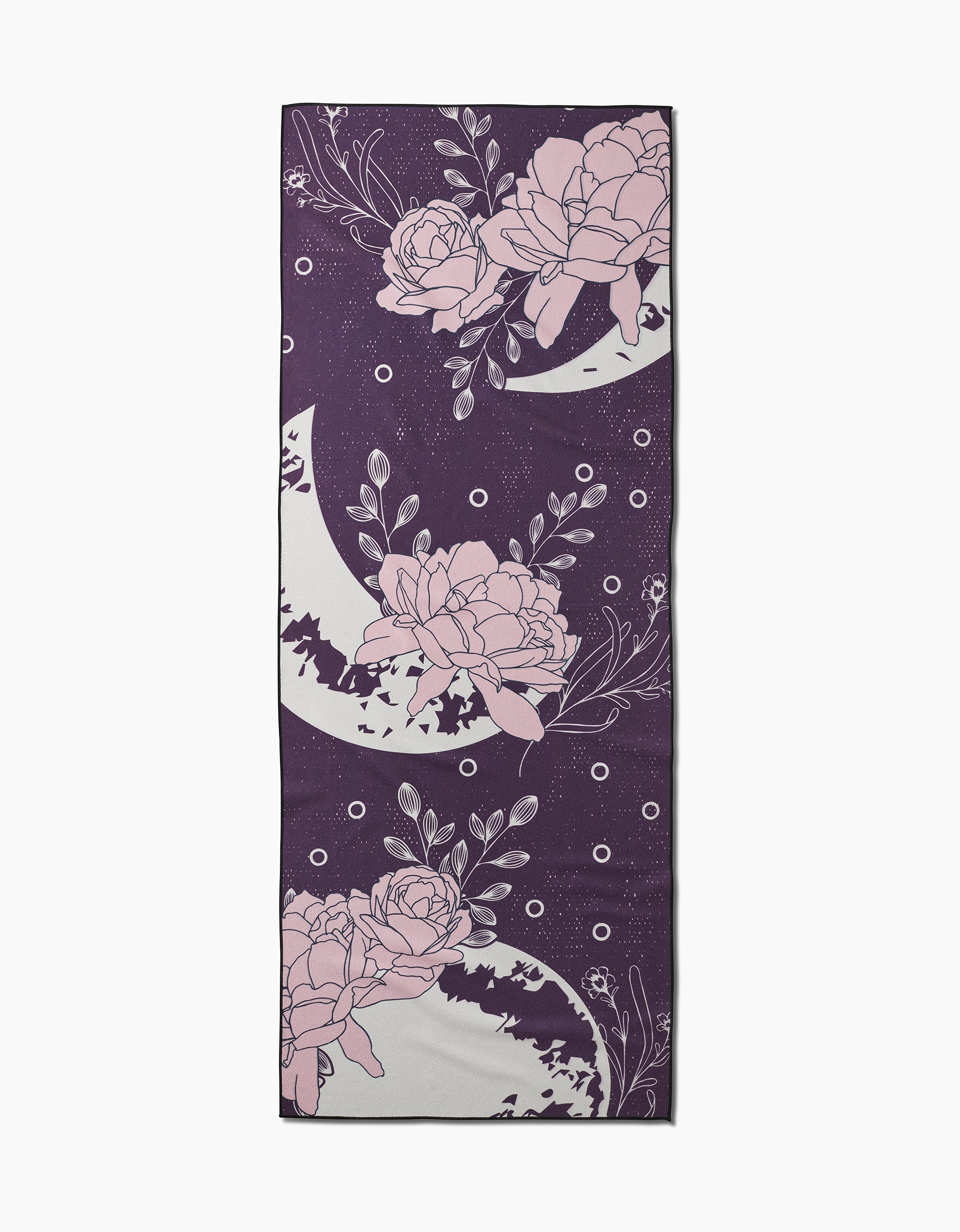 The Ashley Celena Midnight Garden is a rectangular, slip-resistant yoga towel featuring a deep purple background with light pink peonies, white crescent moons, and small white dots in a repeating pattern.