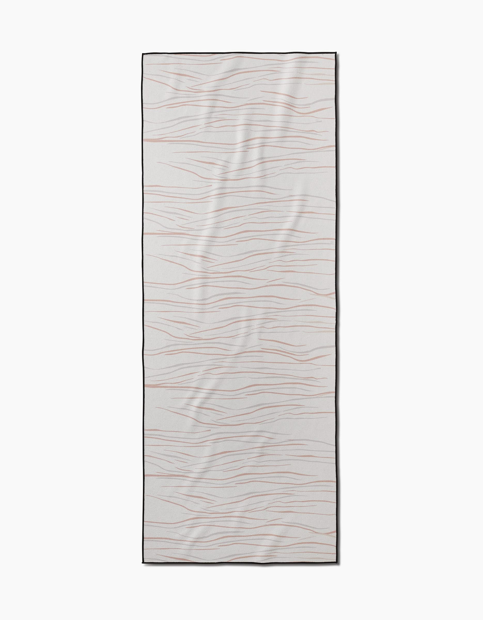 The GEOMETRY Mind yoga towel is rectangular and white, featuring thin, wavy light brown horizontal lines, a slip-resistant texture for stability, and a slim black border around the edges.