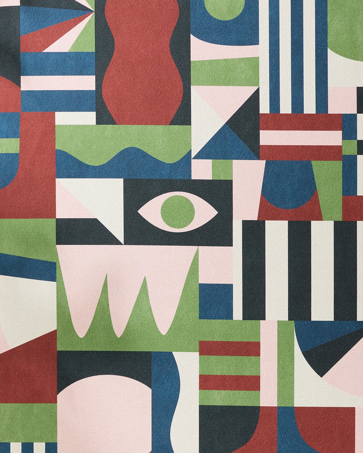 Modern Bauhaus Mood by Claire Iglesias features abstract geometric artwork with stripes, triangles, waves, a central eye, and bold forms in pink, green, red, blue, black, and white—evoking the innovative style of a recycled yoga towel.