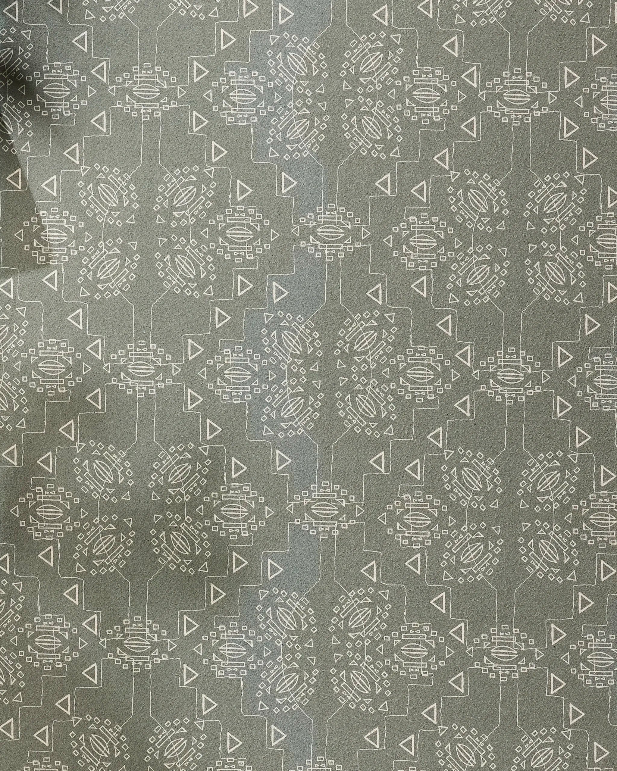 The Ash Cascade "Mountain Bloom" recycled yoga towel features gray fabric with a geometric pattern of white circular shapes made of small lines and dots, connected by lines and triangles. The left edge appears slightly wrinkled.