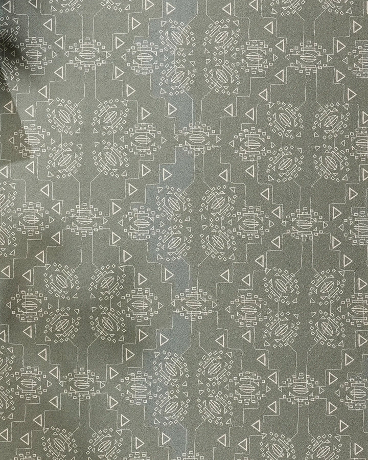 The Ash Cascade "Mountain Bloom" recycled yoga towel features gray fabric with a geometric pattern of white circular shapes made of small lines and dots, connected by lines and triangles. The left edge appears slightly wrinkled.