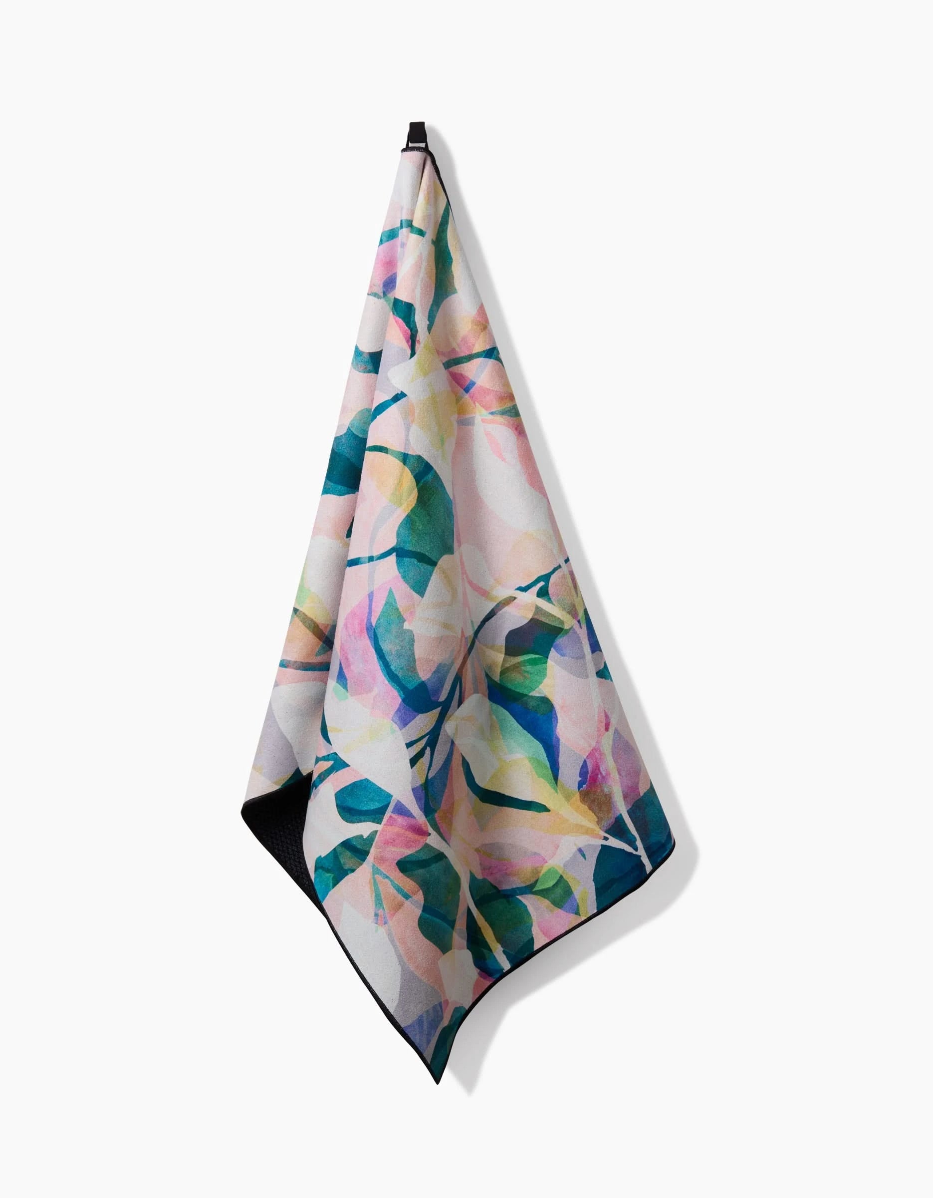 The Rachel Parker Painted Foliage yoga towel features a vibrant watercolor leaf design in pink, green, blue, and yellow. Made from post-consumer recycled materials, it hangs softly against a plain white background.