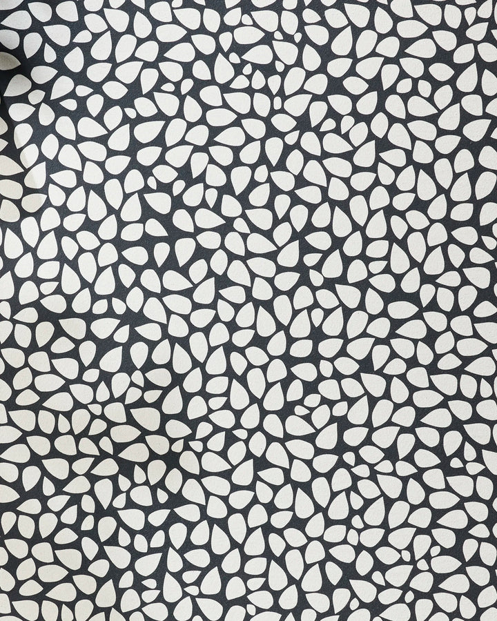 The Pebbles yoga towel by Marina Solodka features an abstract pattern of white pebble shapes on black, offering stylish texture and a dense design for enhanced grip and non-slip performance during your yoga practice.