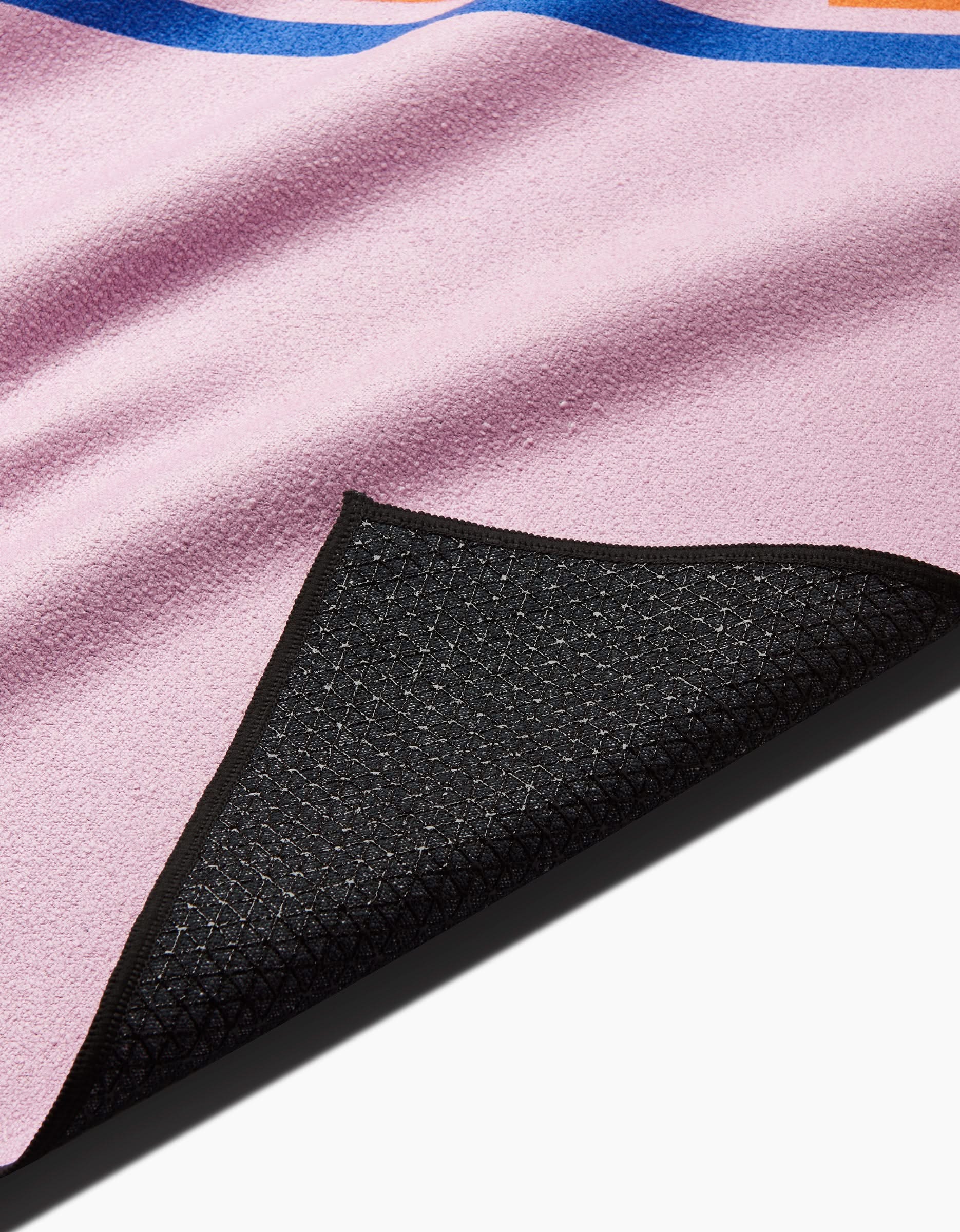 A close-up shows the Happy Hemera Pink Illusion yoga towel with a corner flipped to reveal its textured black silicone non-slip backing and neatly stitched edges.