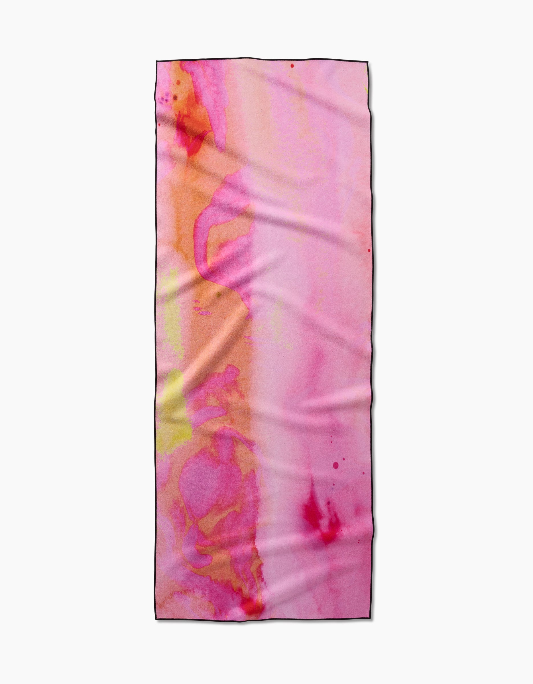 The Geometry “Purity” rectangular yoga towel is made from recycled materials and features a pink, orange, and yellow watercolor pattern with subtle creases on a plain white background.