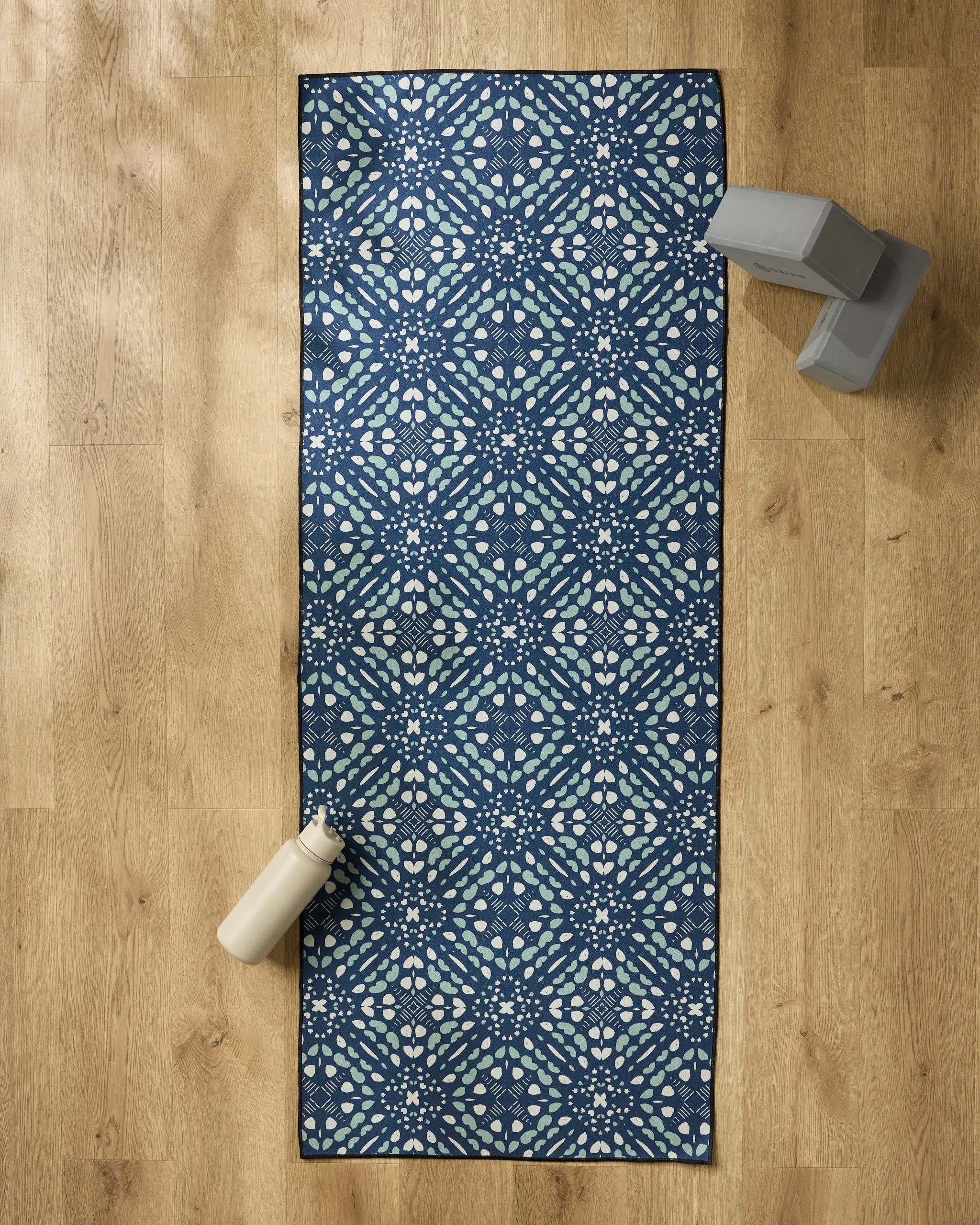 A package of Seeds and Nuts by Twig + Spark rests on a wooden floor, with a water bottle and yoga blocks stacked nearby.