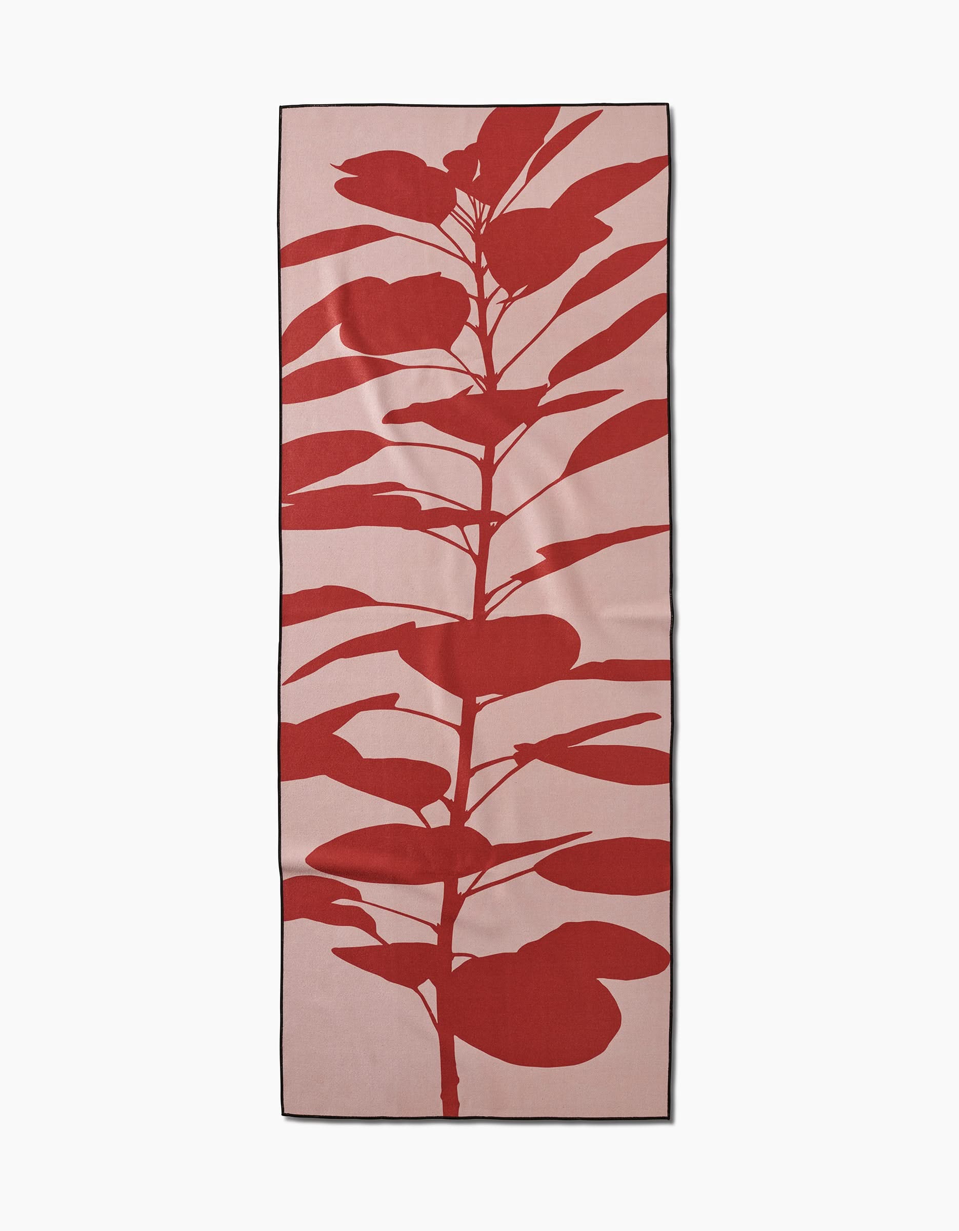 The PrintedPlant Smoketree yoga towel features a large red leafy plant silhouette on light pink with a black border. Made from recycled materials. Rectangular design.