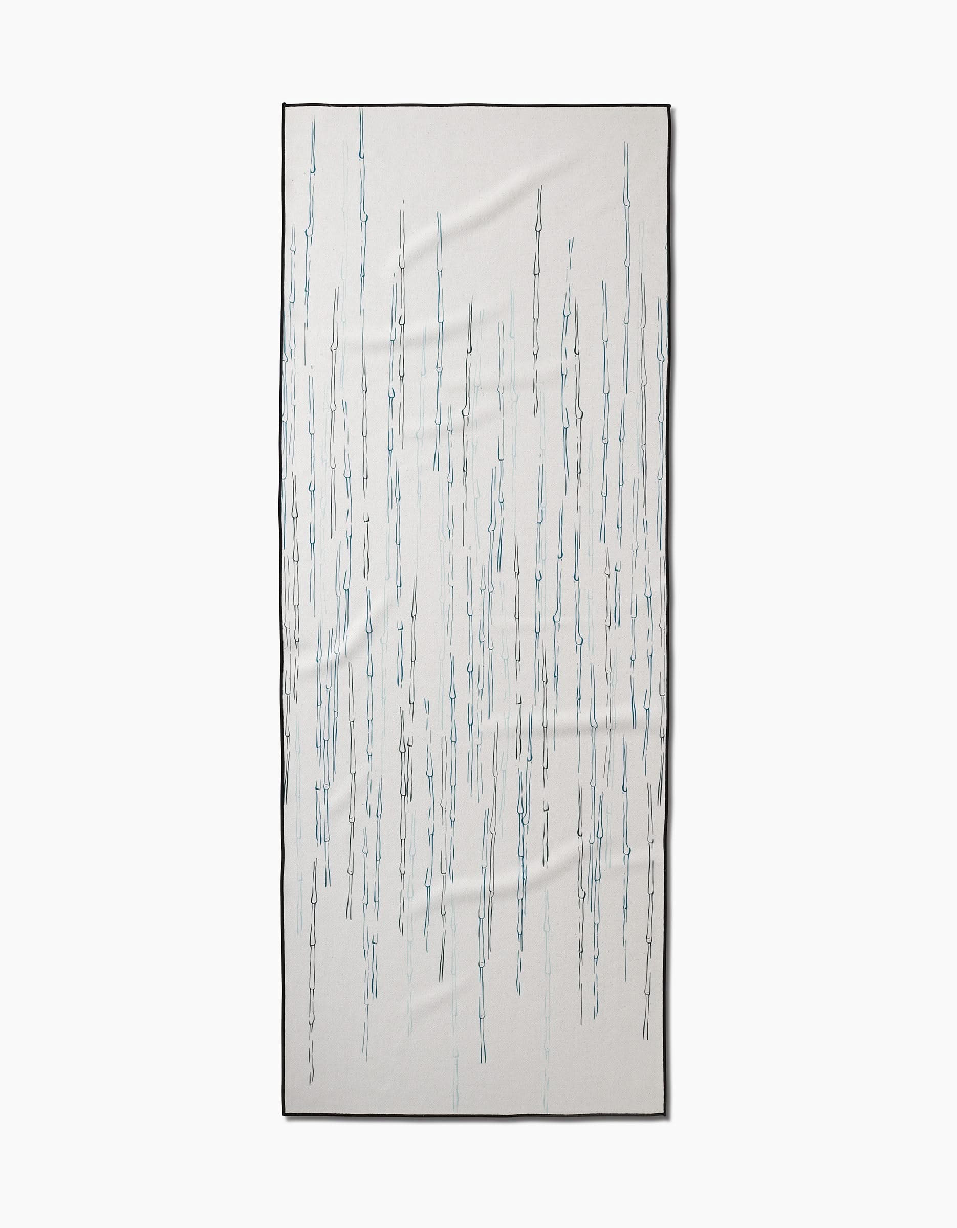 The GEOMETRY Stilts yoga towel is rectangular, white, and non-slip, featuring thin vertical wavy blue and gray lines with a thin black border. It is shown laid flat on a plain white background.