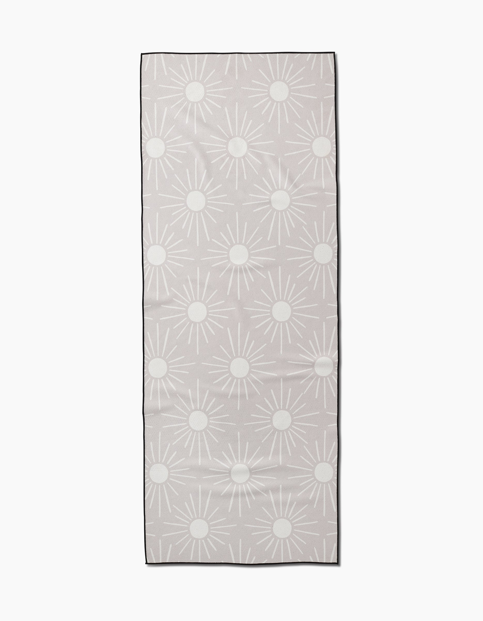 The Sunny Geo yoga towel by Hufton Studio is a rectangular beige towel featuring a repeating pattern of white sun shapes with circular centers and radiating lines on a plain background.