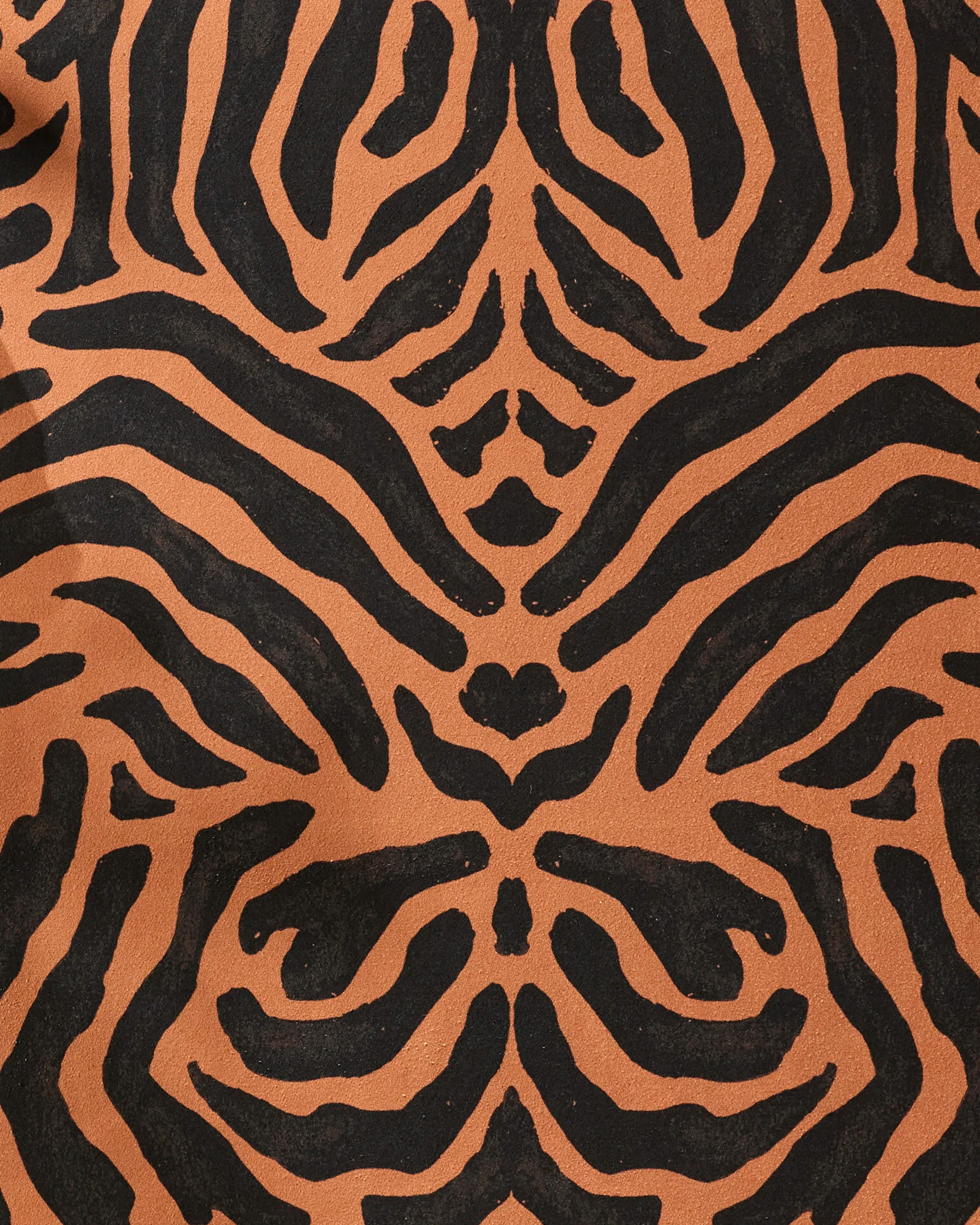 Close-up of the GEOMETRY Tiger yoga towel features a black and orange tiger stripe pattern on a textured, slip-resistant surface, highlighting its symmetrical, abstract design.