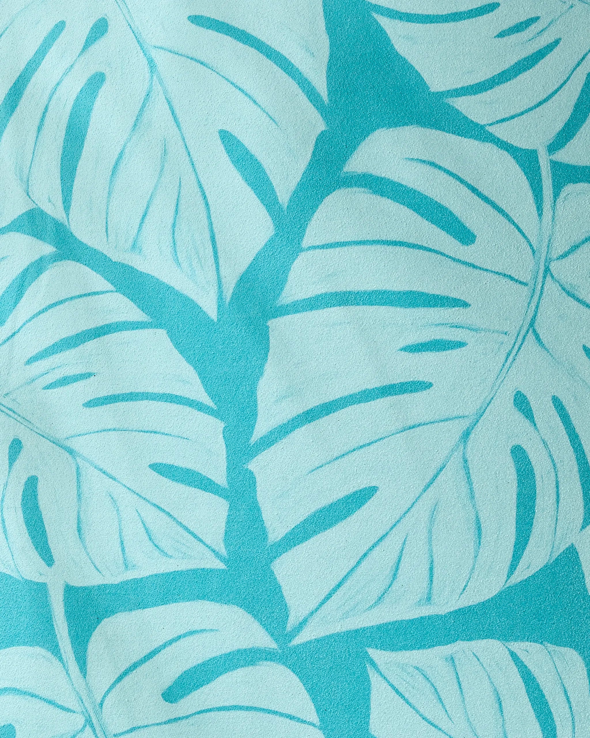 Close-up of the GEOMETRY Tropical recycled yoga towel, showcasing blue and light turquoise tropical leaves with large overlapping patterns and prominent veins.
