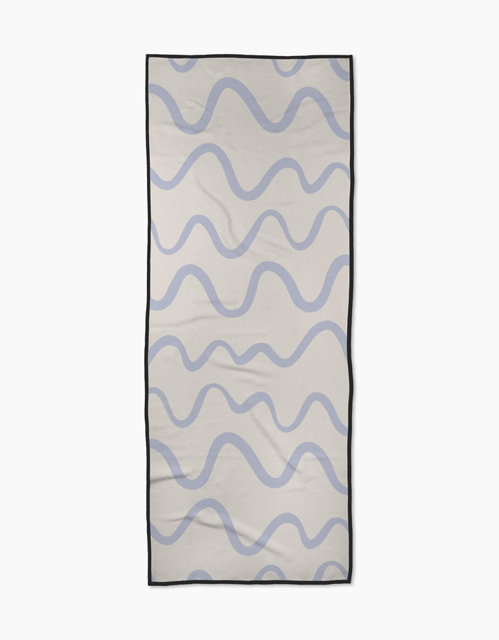 The Wavy Stripe in Blue yoga towel by Teri the Butter is a rectangular, recycled towel featuring wavy blue lines on a light beige background with a thin black border.