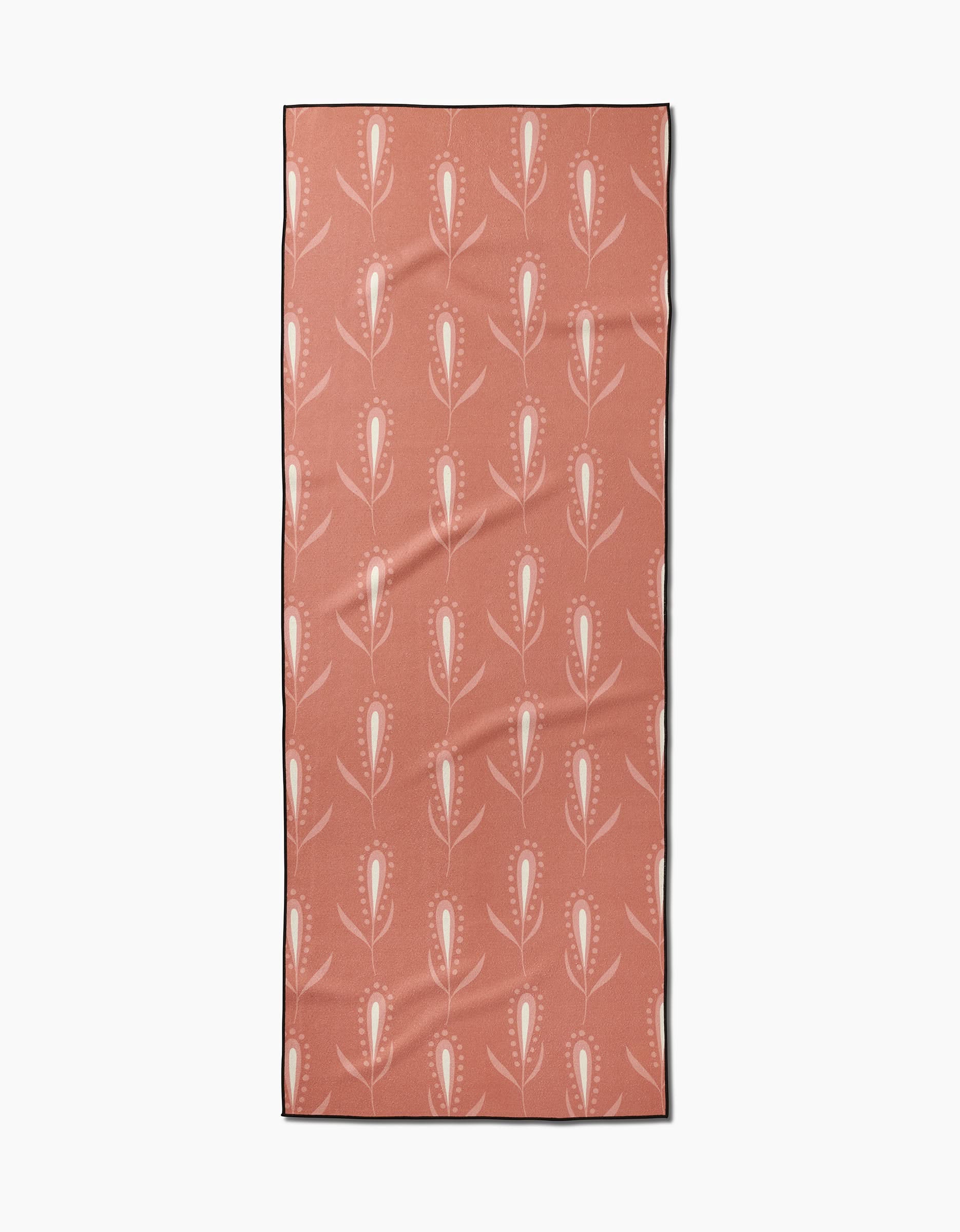 The Wilds yoga towel by Amita Nair features a rectangular pink design with white and red abstract tulip-like flowers in vertical rows, offering slip-resistant support for your practice.