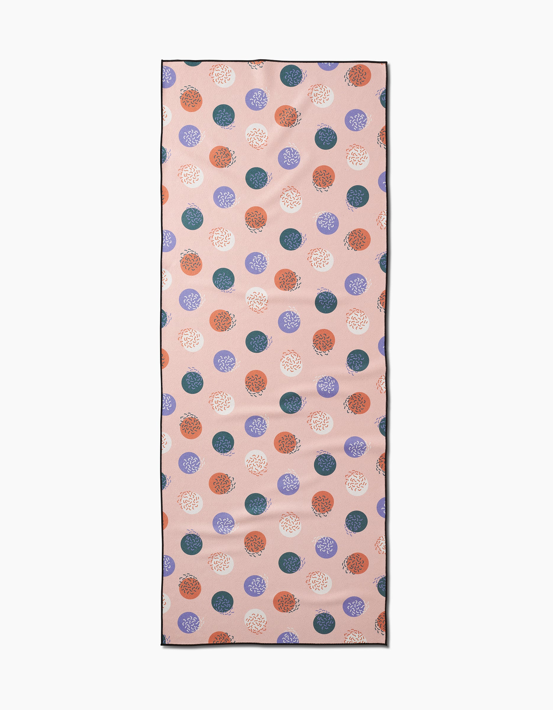 The Wonky Dots yoga towel by Claire Iglesias features a rectangular recycled design with a light pink background and scattered blue, orange, purple, and white polka dots, each adorned with intricate circular patterns.